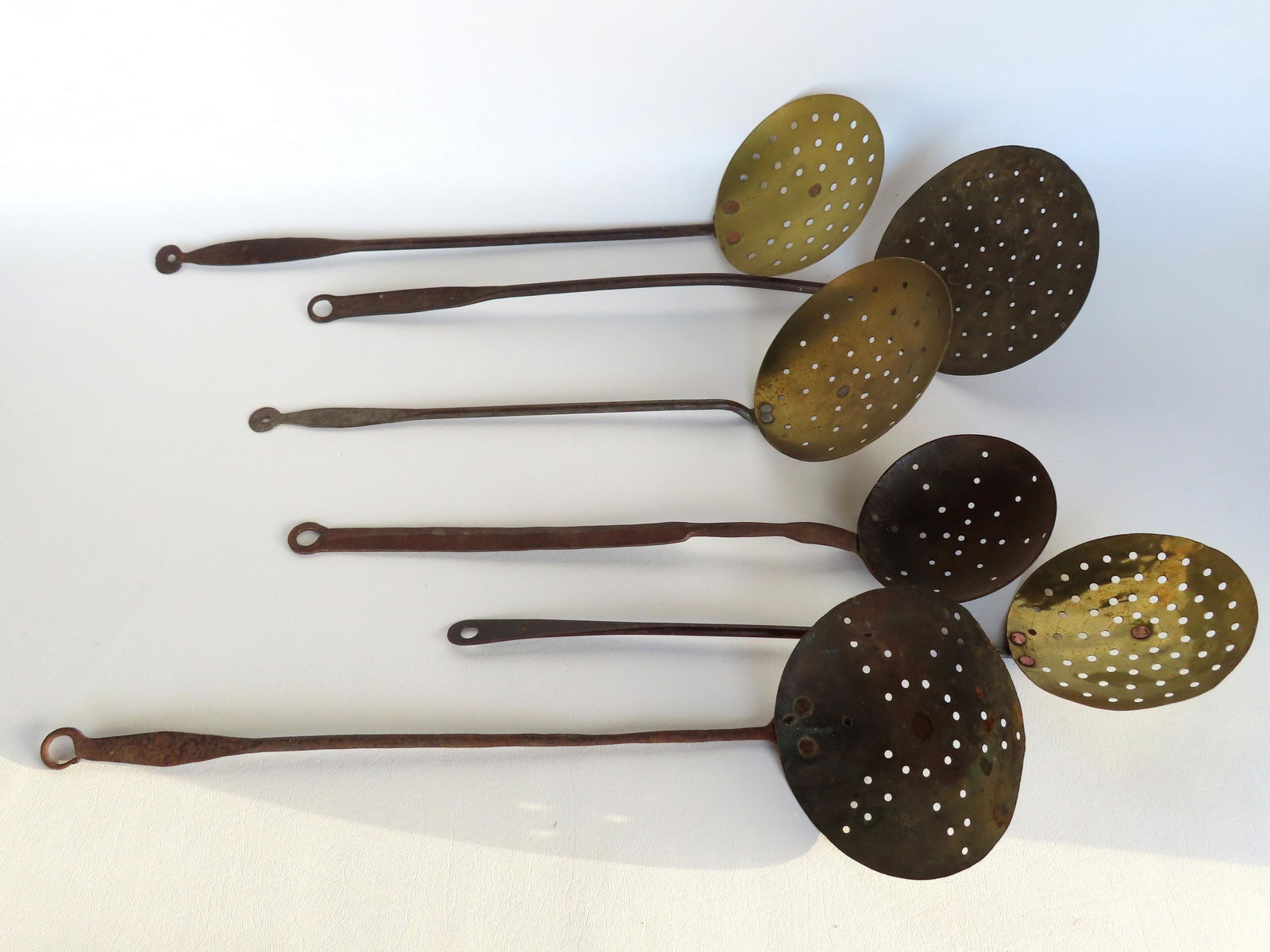 A grouping of 6 early strainers, 19th century, 4 in brass and 2 in iron. All in very good condition.: A grouping of 6 early strainers, 19th century, 4 in brass and 2 in iron. All in very good condition. The largest measures 23 1/2"L.