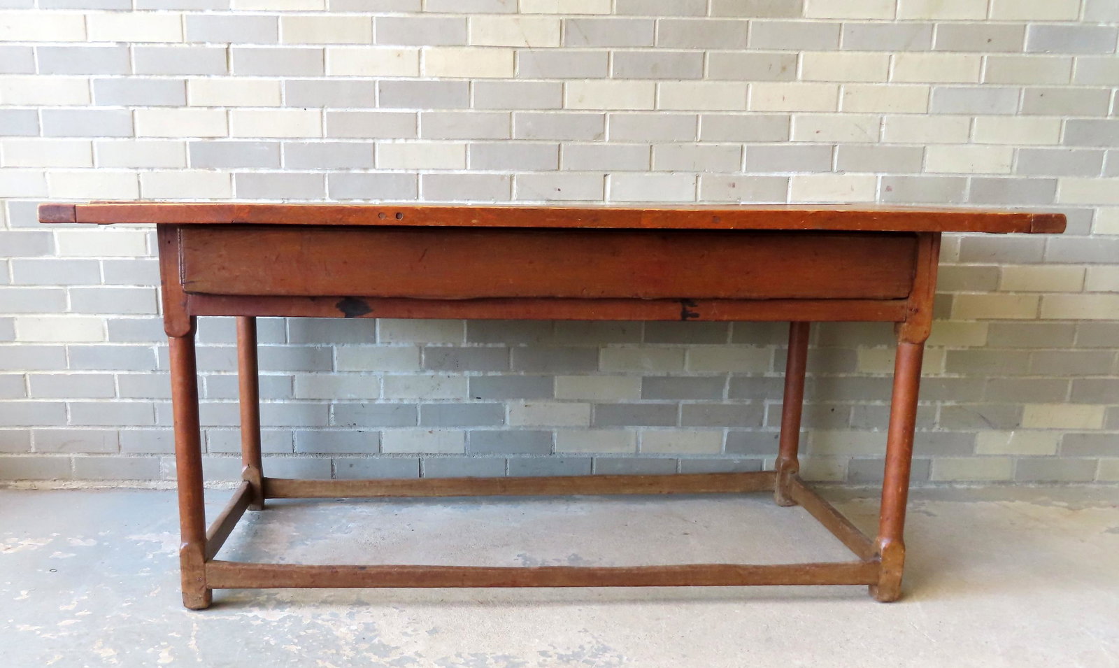 A primitive tavern or kitchen work table, 18th century, with original stretcher base, wide front: A primitive tavern or kitchen work table, 18th century, with original stretcher base, wide front drawer with dovetailed construction, and applied border to top which appears to be all original. Metal 