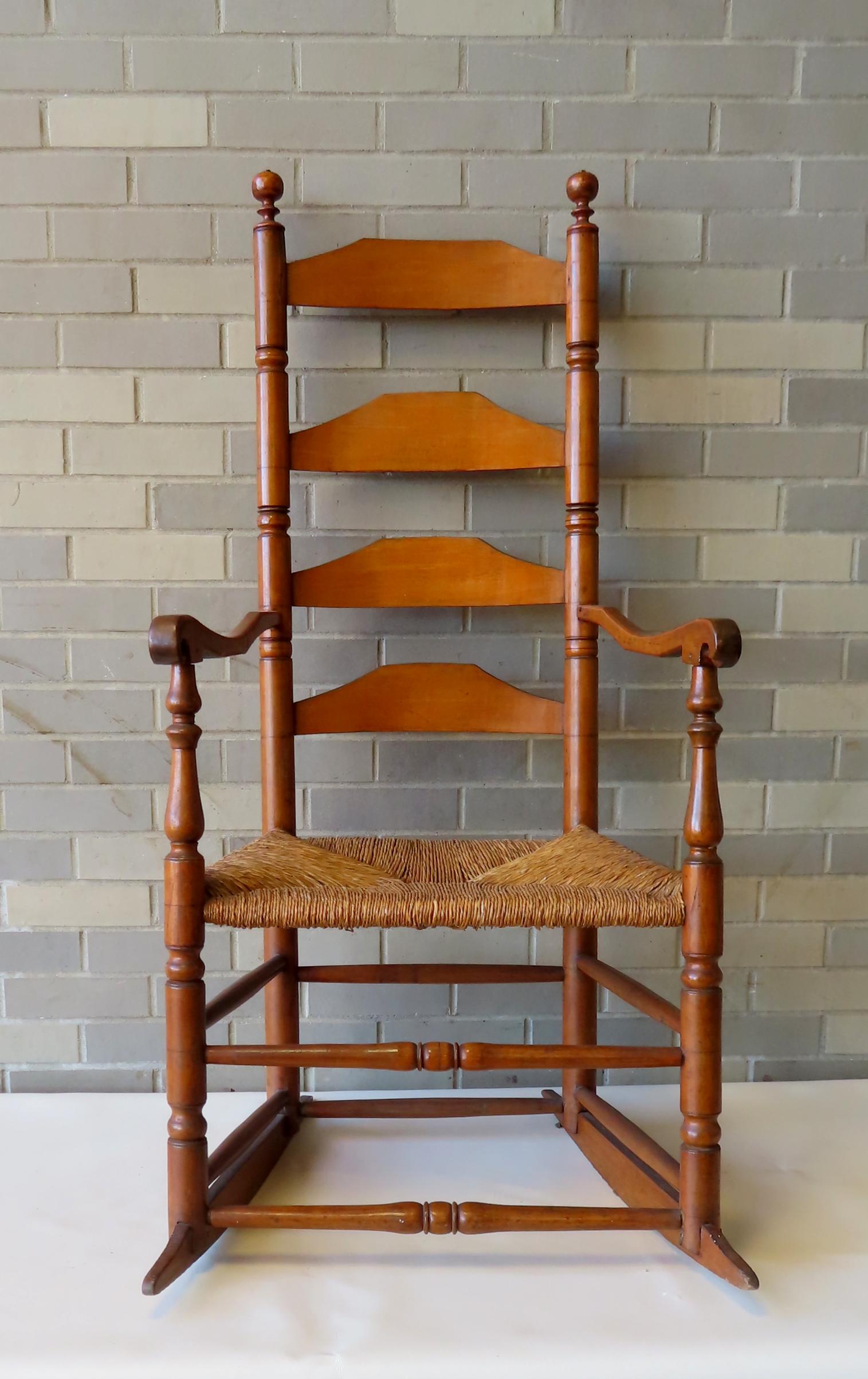 Ladder back rocking chair with scrolled arms, probably New England, late 18th to early 19th century.: Ladder back rocking chair with scrolled arms, probably New England, late 18th to early 19th century. Older rush seat. Small professional repair to one arm where it meets post, otherwise very good cond