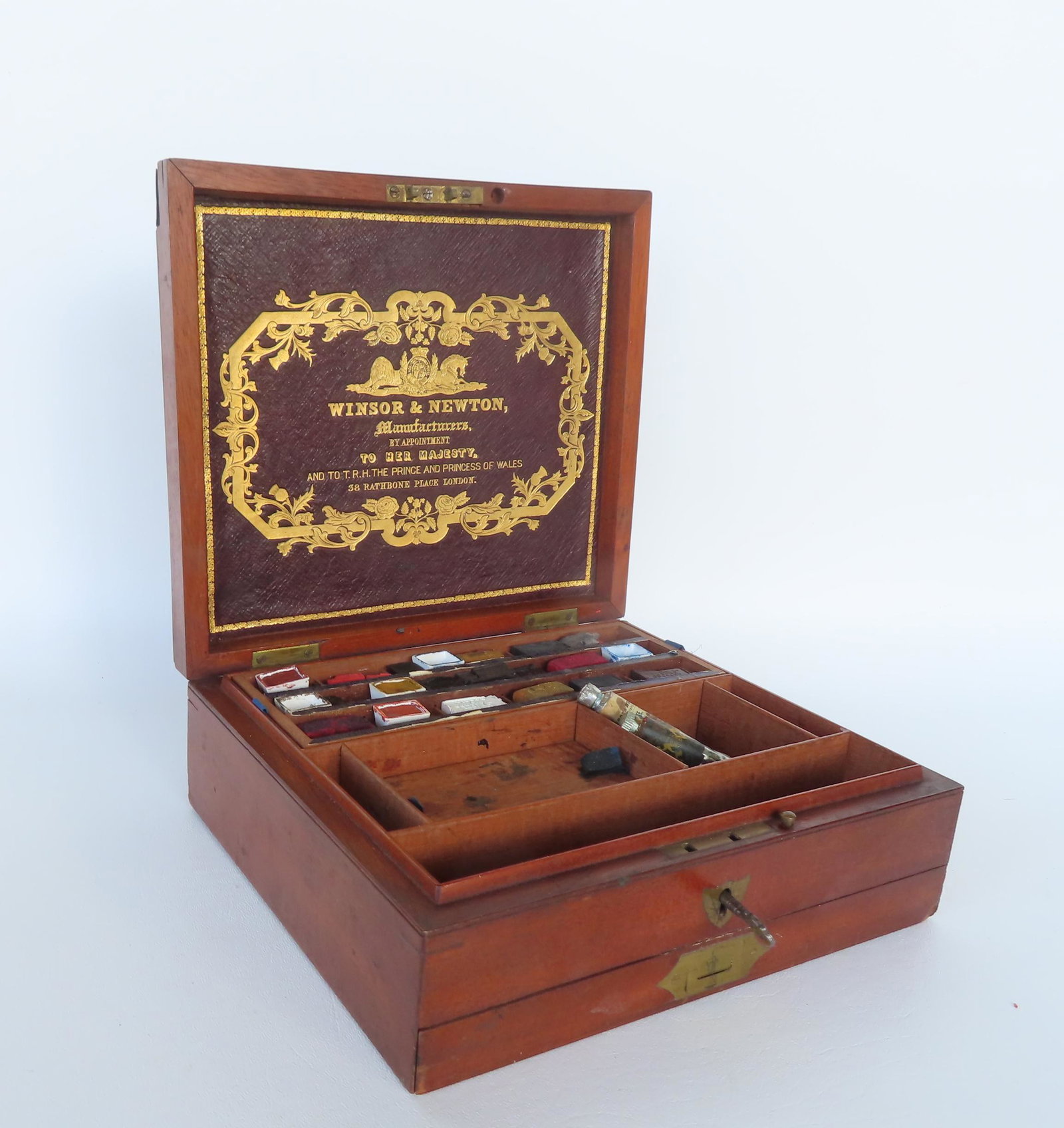 An English figured mahogany watercolorist box with fitted interior and lower drawer containing: An English figured mahogany watercolorist box with fitted interior and lower drawer containing artist supplies including 2 porcelain paint trays, paint brushes and coloring blocks, signed Winsor & New