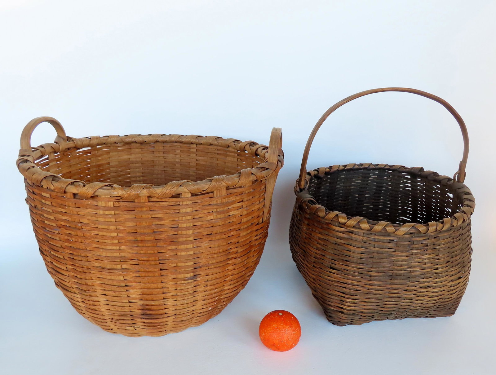Two splint field baskets, late 19th century. The first, swing handle, crisscrossed rim, very good: Two splint field baskets, late 19th century. The first, swing handle, crisscrossed rim, very good condition - no breaks or losses -14" diameter x 11"H; the second basket having 2 small loop handles, c
