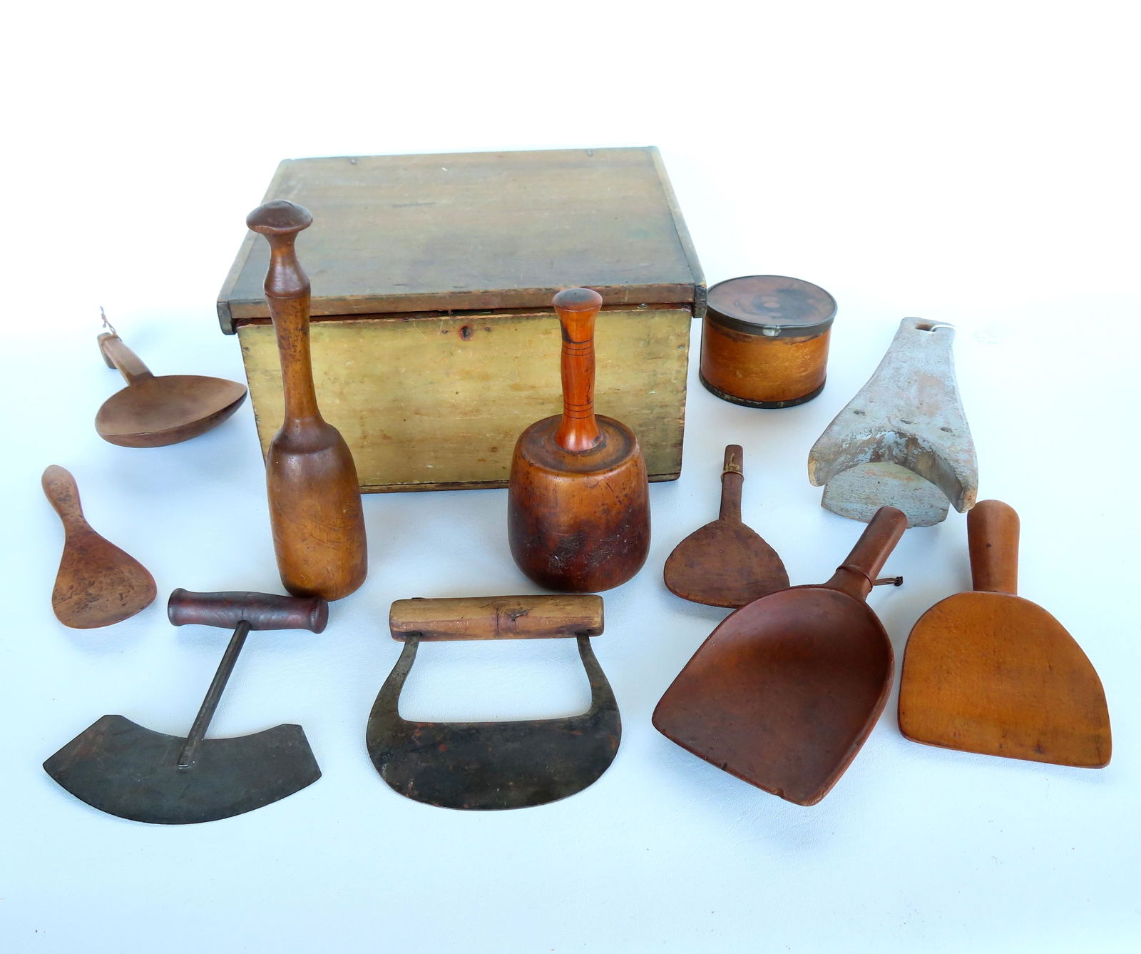 A grouping of country objects including food choppers, wooden butter scoops, 2 pestles, an early: A grouping of country objects including food choppers, wooden butter scoops, 2 pestles, an early document box, a boot jack in original blue/gray paint, etc. The box measures 13"W x 11 1/4"D x 7"H. Mos