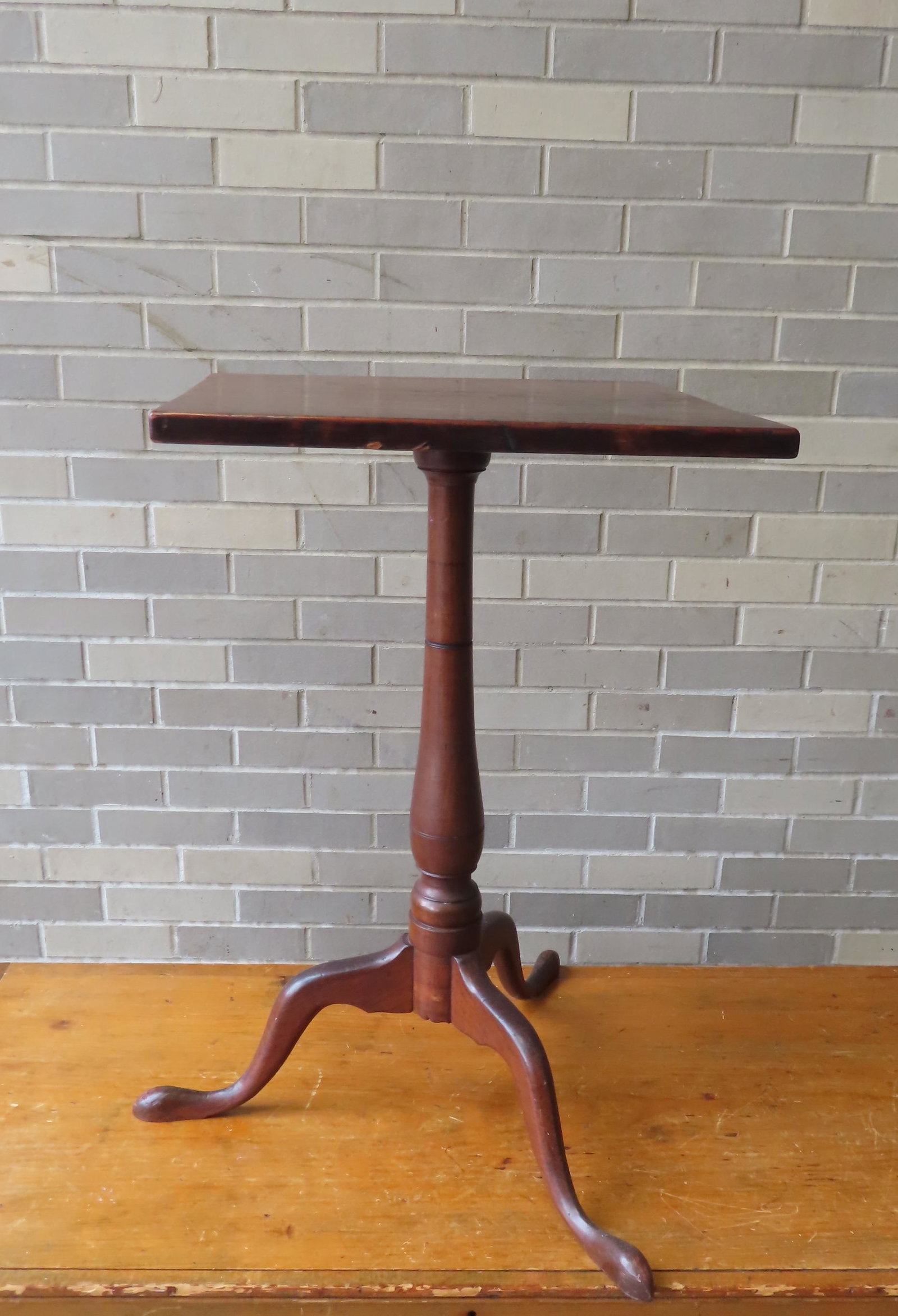 A very fine New England cherry candlestand with square top over turned post attached to original: A very fine New England cherry candlestand with square top over turned post attached to original underside cleat of top, and having snake feet. The stand is in very good untouched condition with minor