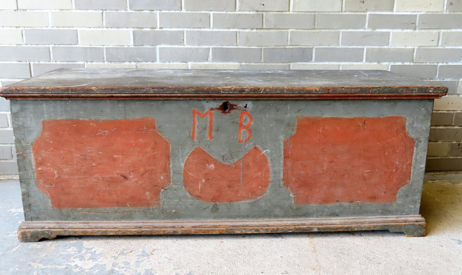 An early Mohawk Valley blanket box in original blue/green paint over salmon base paint to form: An early Mohawk Valley blanket box in original blue/green paint over salmon base paint to form decorations on the front and sides typical from this region and also initialed MB across the front, mount