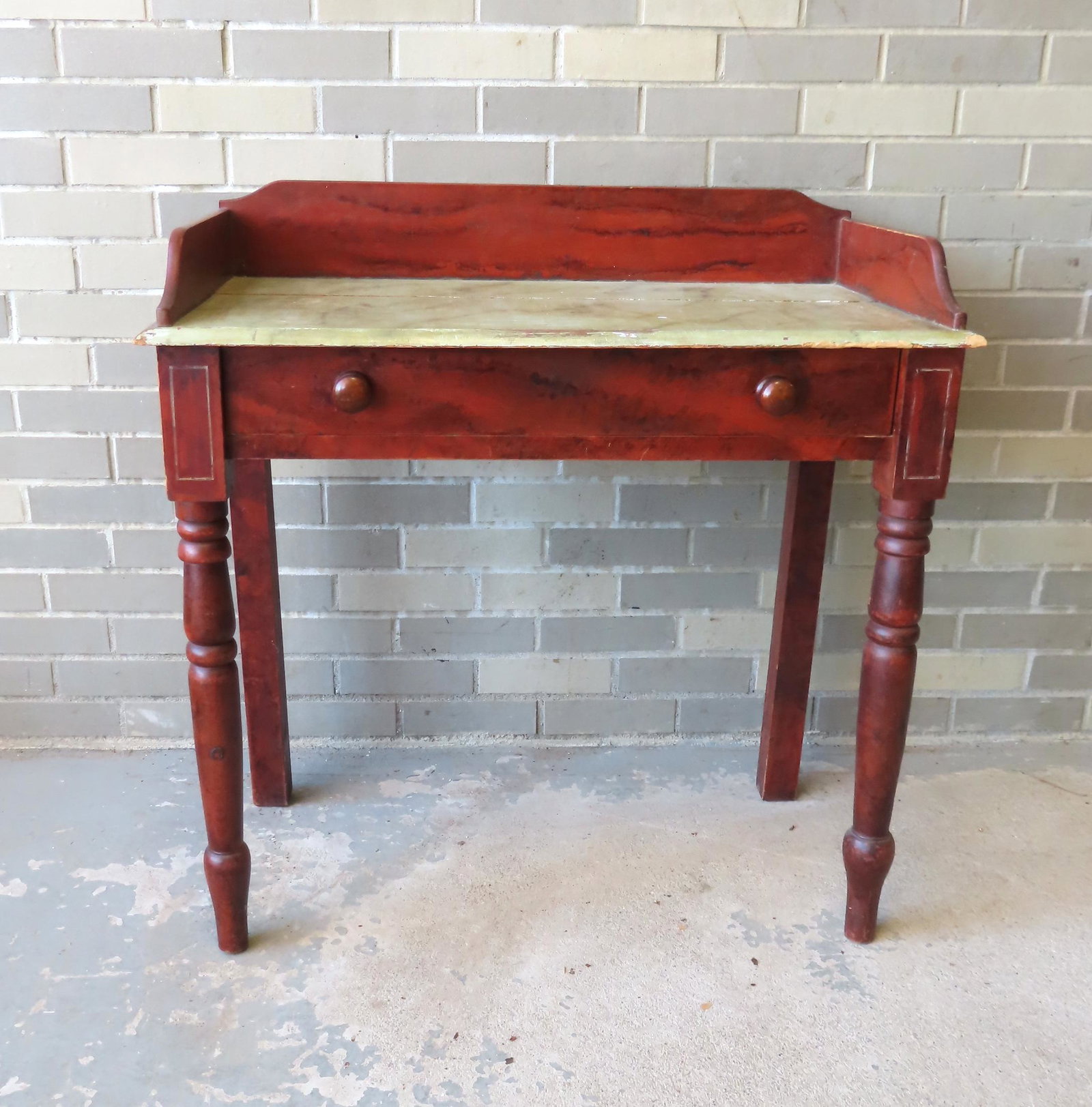 A country grain painted work table having gallery top over 1 drawer with original turned wooden: A country grain painted work table having gallery top over 1 drawer with original turned wooden pull, turned front legs, and smoke grained top. Normal use wear to top, and overall very good condition.