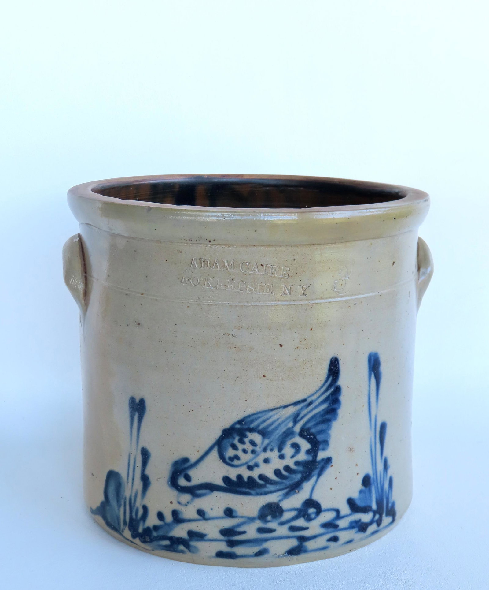 A stoneware crock decorated with a chicken pecking corn in foliage with the impressed mark of Adam: A stoneware crock decorated with a chicken pecking corn in foliage with the impressed mark of Adam Caire Poughkeepsie NY. 10 1/2'H x 11 1/2" diameter. Professional restoration to rim, and repair to ri