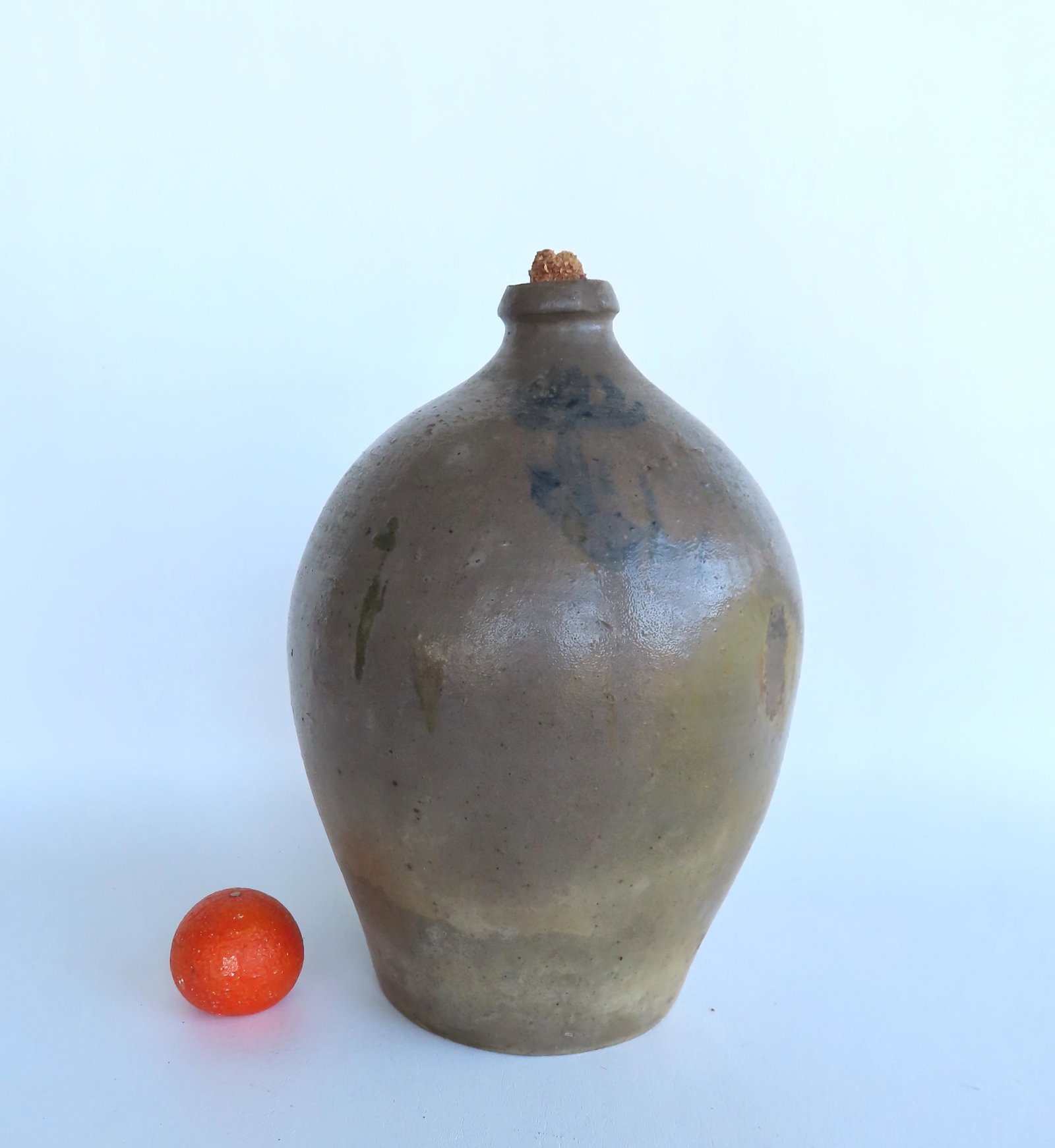 An ovoid jug decorated with a faint blue flower, 4 gallon size, note the corn cobb stopper - some: An ovoid jug decorated with a faint blue flower, 4 gallon size, note the corn cobb stopper - some staining, but overall very good condition. 16"H x 12"W.