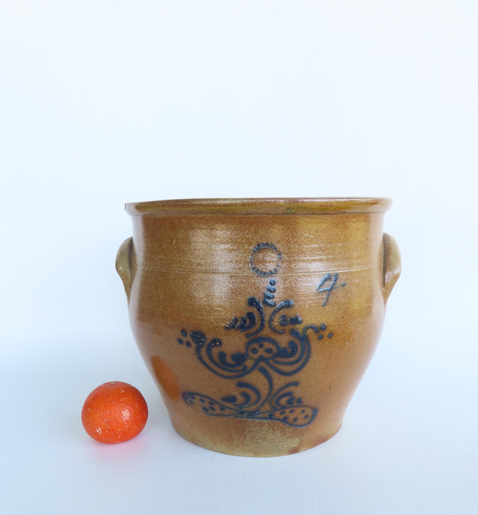 A stoneware ovoid crock decorated with a cobalt blue flower, with the circular impressed mark of: A stoneware ovoid crock decorated with a cobalt blue flower, with the circular impressed mark of Jacob Caire Poughkeepsie NY, circa 1850, 4 gallon size - several small chips around edge of rim, a "Y" 