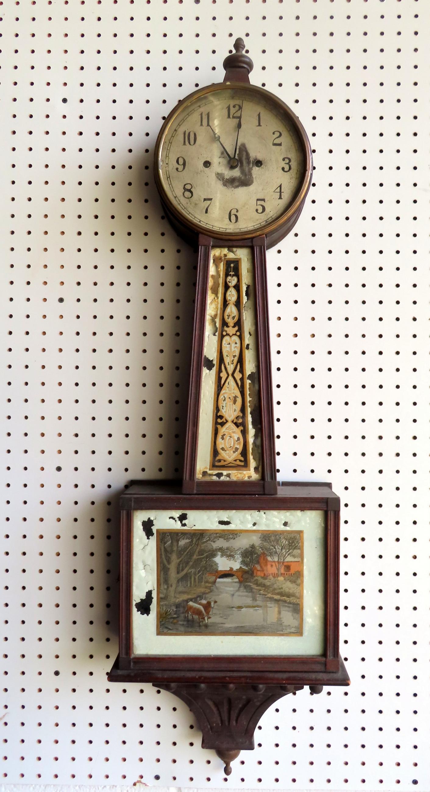 A New Haven Clock Co. banjo clock, early to mid 19th century. Losses to reverse paintings, finial: A New Haven Clock Co. banjo clock, early to mid 19th century. Losses to reverse paintings, finial may be a replacement, wear to clock face, but very good running condition. While this clock has been r