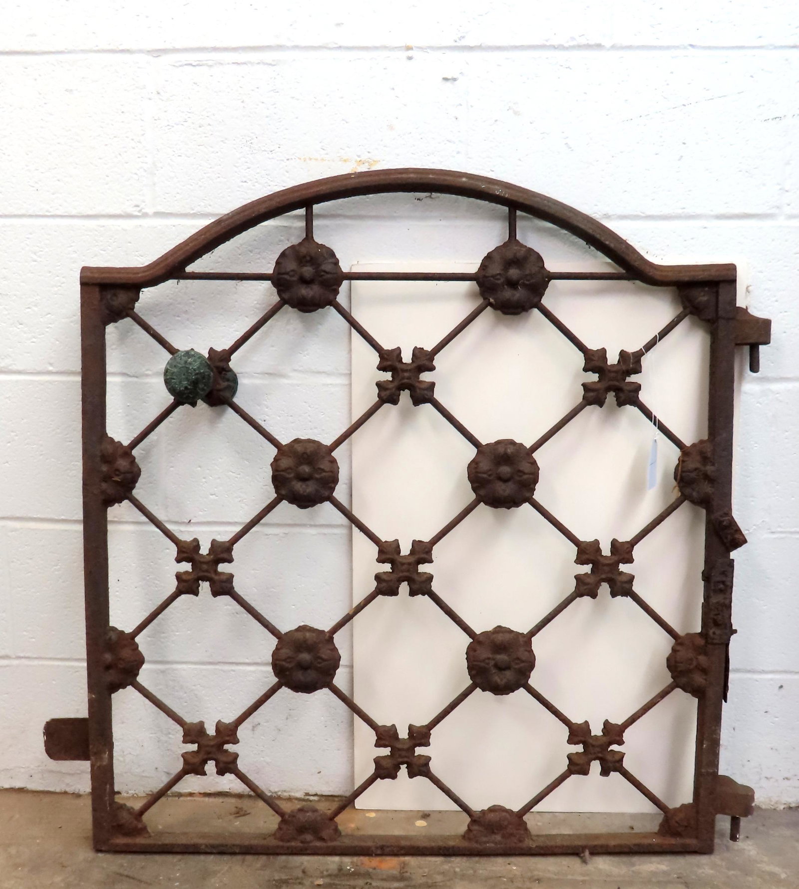 A cast iron garden gate with original ornate brass door knobs and decorated with floral medallions,: A cast iron garden gate with original ornate brass door knobs and decorated with floral medallions, mid to late 19th century - note a repair to side rail that would attach to post, rust and some pitti