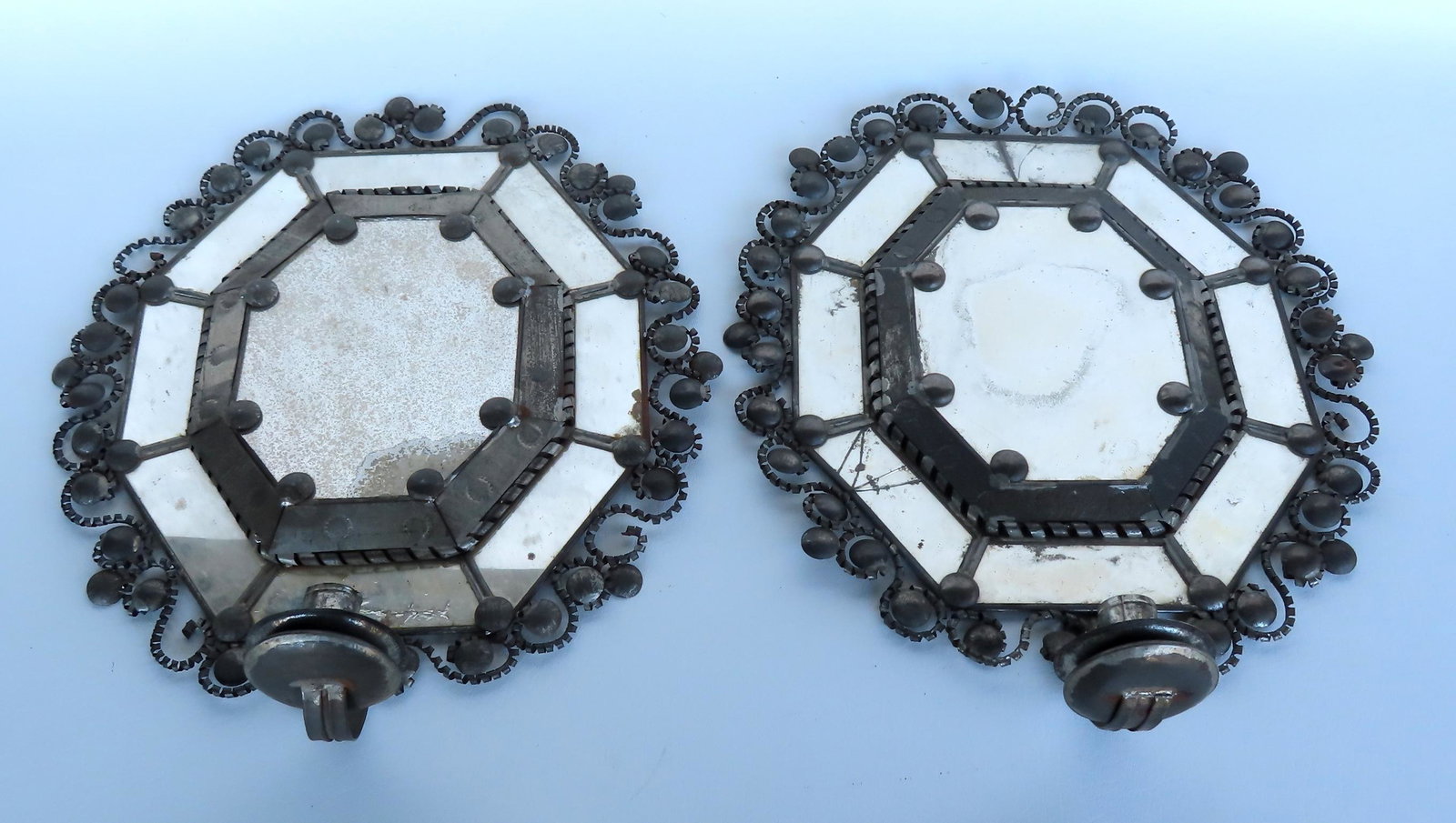 Two unusual custom made tin candle wall sconces with mirror backs, probably early to mid 20th: Two unusual custom made tin candle wall sconces with mirror backs, probably early to mid 20th century. Several of the tin circular ornaments are missing, 2 of the border panel mirrors have cracks, els