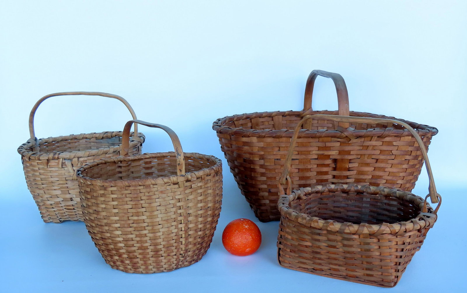 Grouping of 4 good splint baskets, late 19th to early 20th century. A swing handle round basket with: Grouping of 4 good splint baskets, late 19th to early 20th century. A swing handle round basket with square bottom and double wrapped rim -very good condition, no damage - measures 11 1/4"W x 6"H; a r