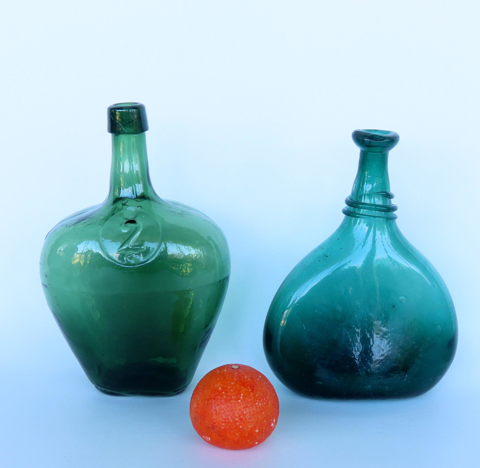 Two early bottles. The first a green Persian saddle flask with scarred pontil, late 18th to early: Two early bottles. The first a green Persian saddle flask with scarred pontil, late 18th to early 19th century - 10"H x 7 1/2"W - very good condition; and a small 2 demijohn bottle marked "2" within c
