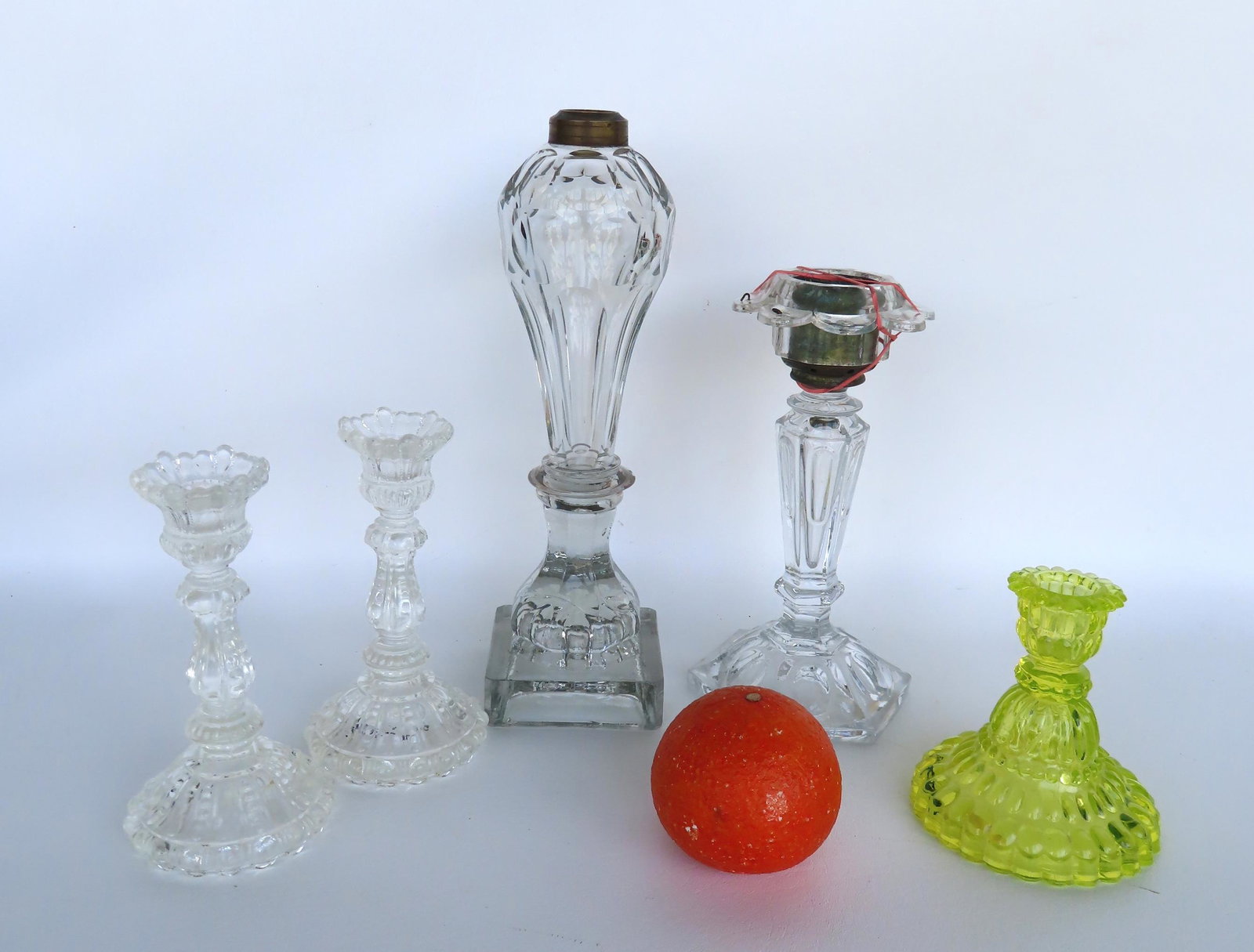 Grouping of 5 early lighting devices including a whale oil lamp (no burner), an unusual glass candle: Grouping of 5 early lighting devices including a whale oil lamp (no burner), an unusual glass candle holder with tin font, and 3 candle holders that appear to be Sandwich. All believed to be early to 