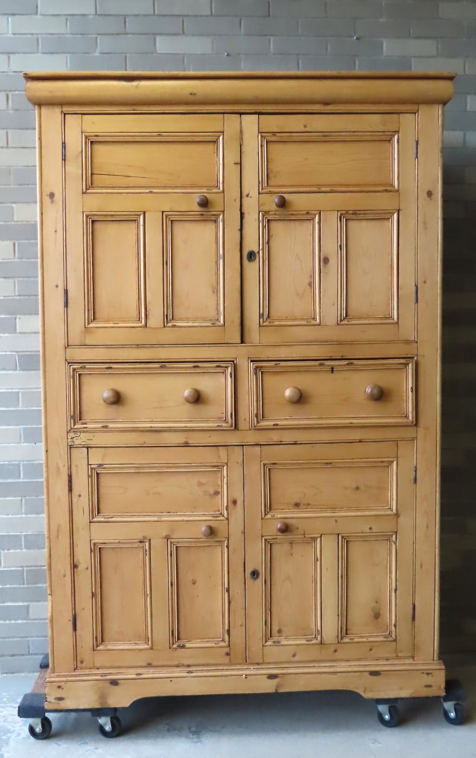 A scrubbed pine kitchen cupboard, 19th century: A scrubbed pine kitchen cupboard having 2 paneled doors over 2 drawers over 2 paneled doors on cutout base. Part of backboard has been cutout to accommodate an appliance, else very good condition. Mid