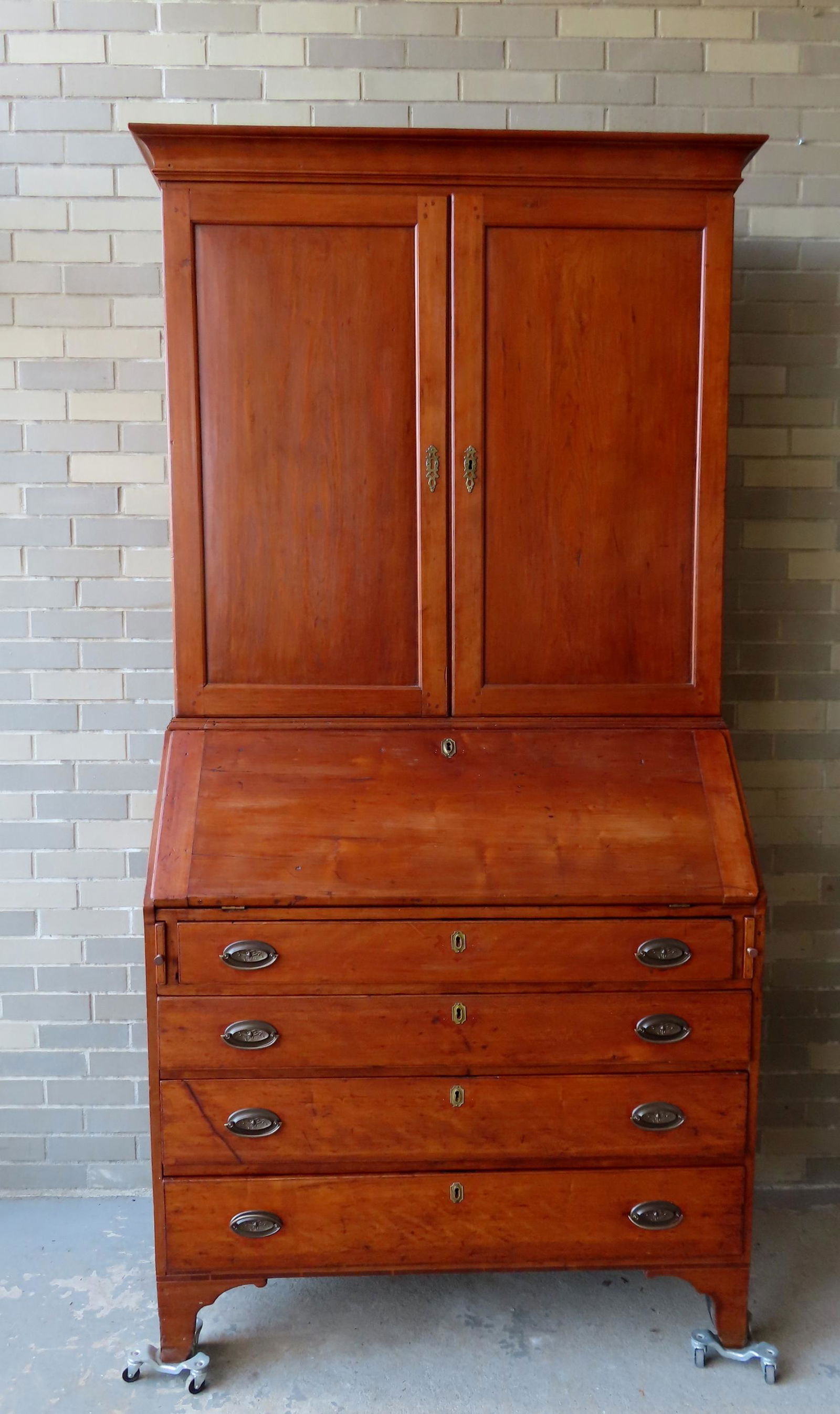 An American country Hepplewhite cherry secretary  cabinet having 2 paneled doors over a slant front (1 of 20)