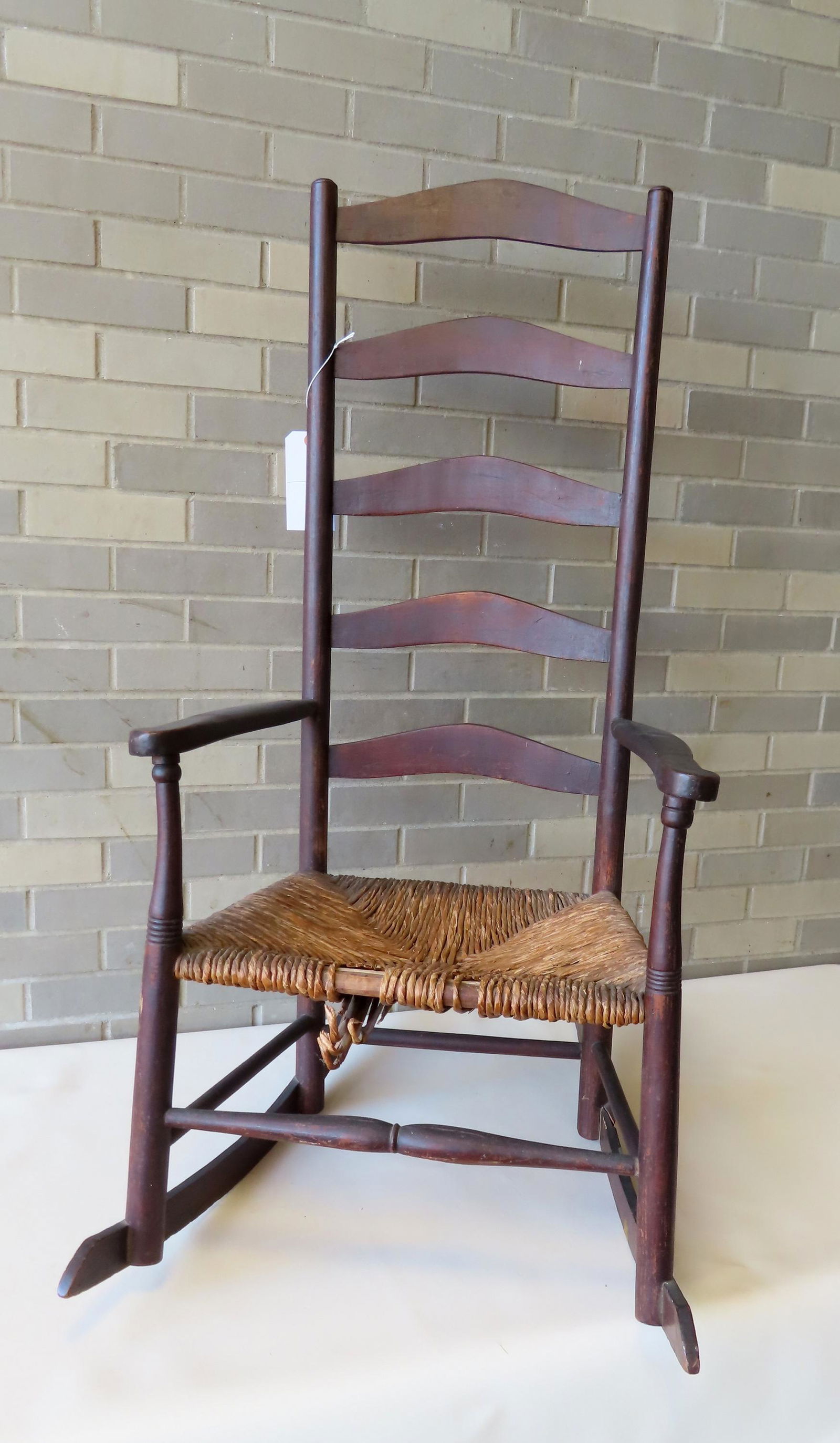 Ladder back rocker with 5 curved slats, slightly scrolled arms, rush seat with losses, and original (1 of 7)