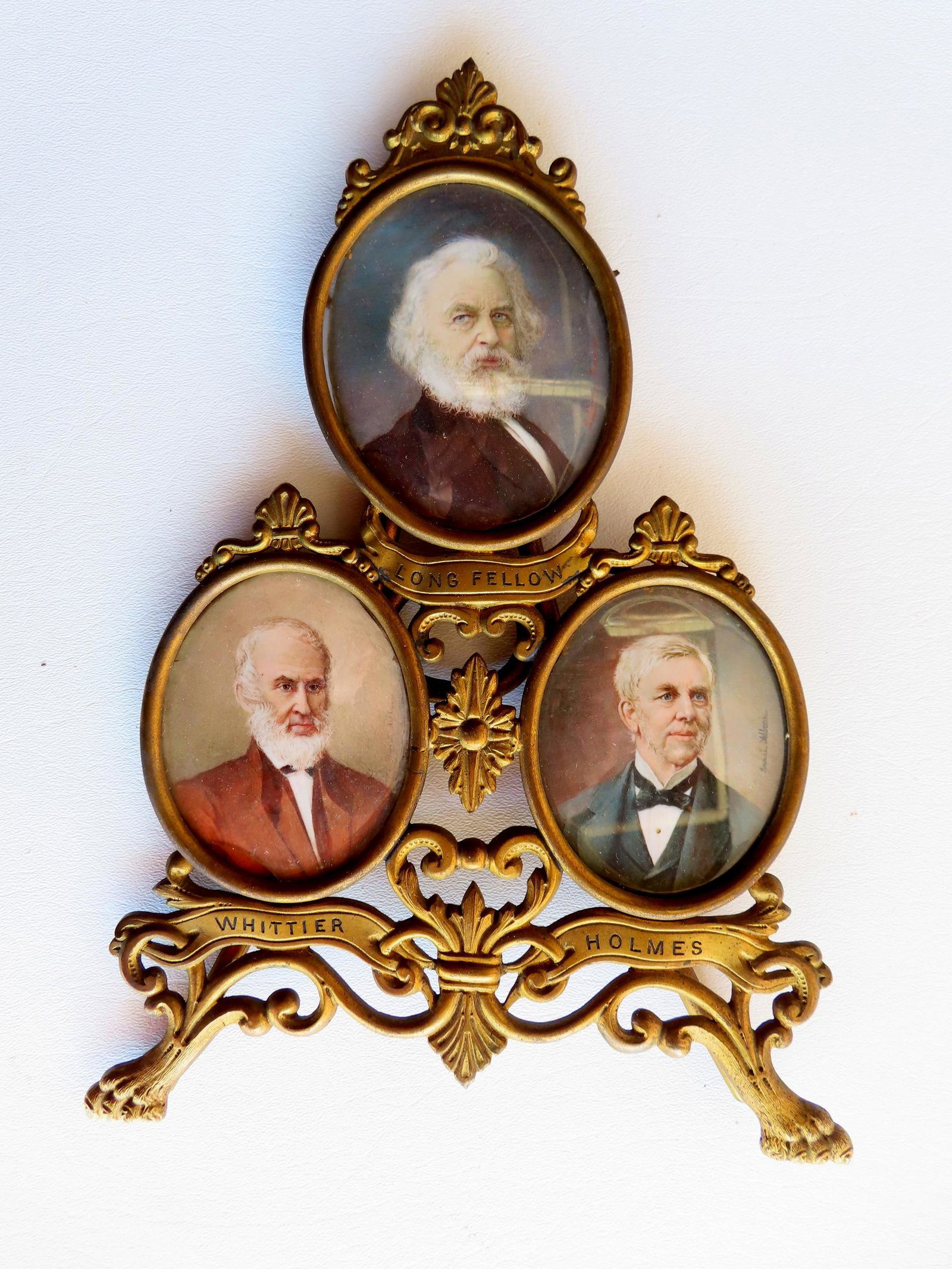 Three miniature oil portraits of famous authors including Whittier, Longfellow and Holmes, mounted: Three miniature oil portraits of famous authors including Whittier, Longfellow and Holmes, mounted in a gilt brass triptych standup dresser frame with claw feet, 19th century - all appear to be signed