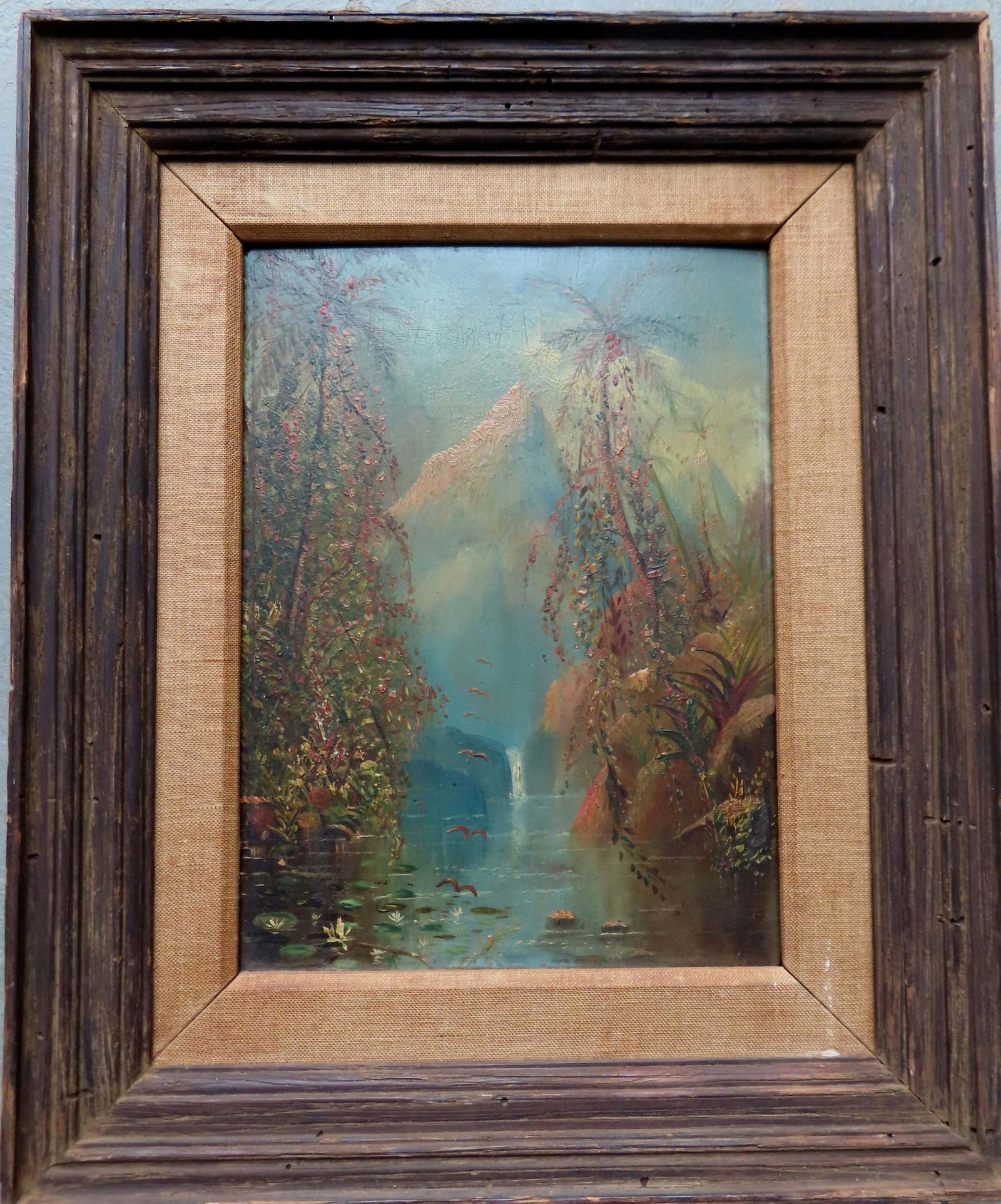 O/B Palm trees by river with waterfall and peaked mountains in background, probably early 20th: O/B Palm trees by river with waterfall and peaked mountains in background, probably early 20th century. Total frame size 13 1/2" x 16 1/4". Note "House of Heydenryk" NY label on reverse".