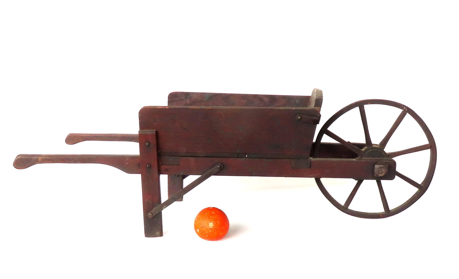 A 19th century child's wheel barrow with wooden wheels in original dark red/brown stain, very good: A 19th century child's wheel barrow with wooden wheels in original dark red/brown stain, very good condition. Measures 37 1/2"L x 12 1/2"W x 11 1/2"H.