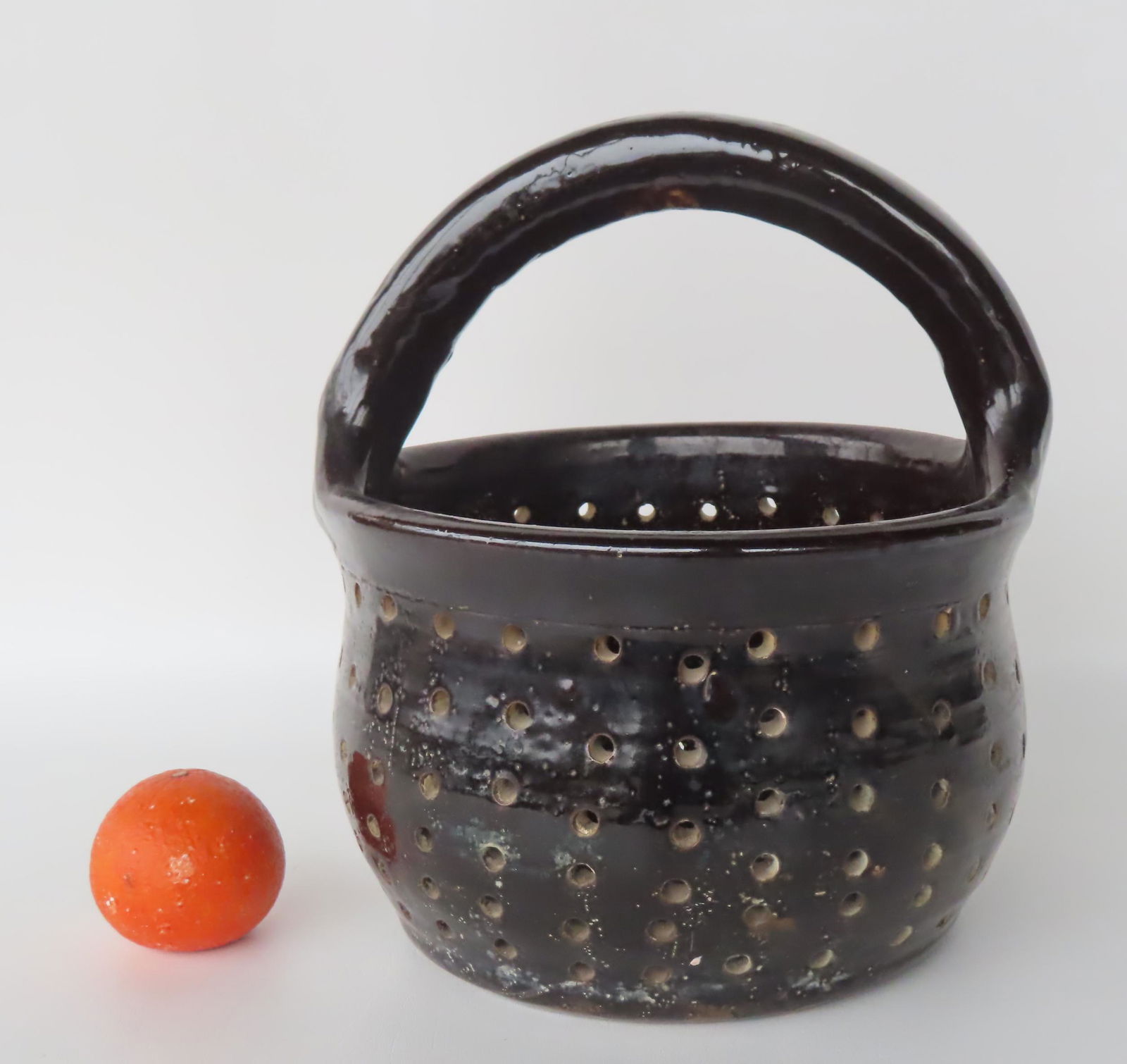 An unusual stoneware strainer with single overhead loop handle, in a glossy manganese glaze, 19th (1 of 7)