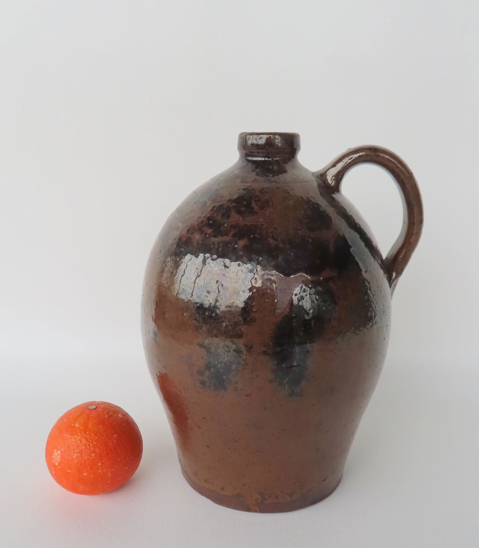 A redware jug with applied handle, slightly ovoid, having manganese decorations over a light brown (1 of 11)