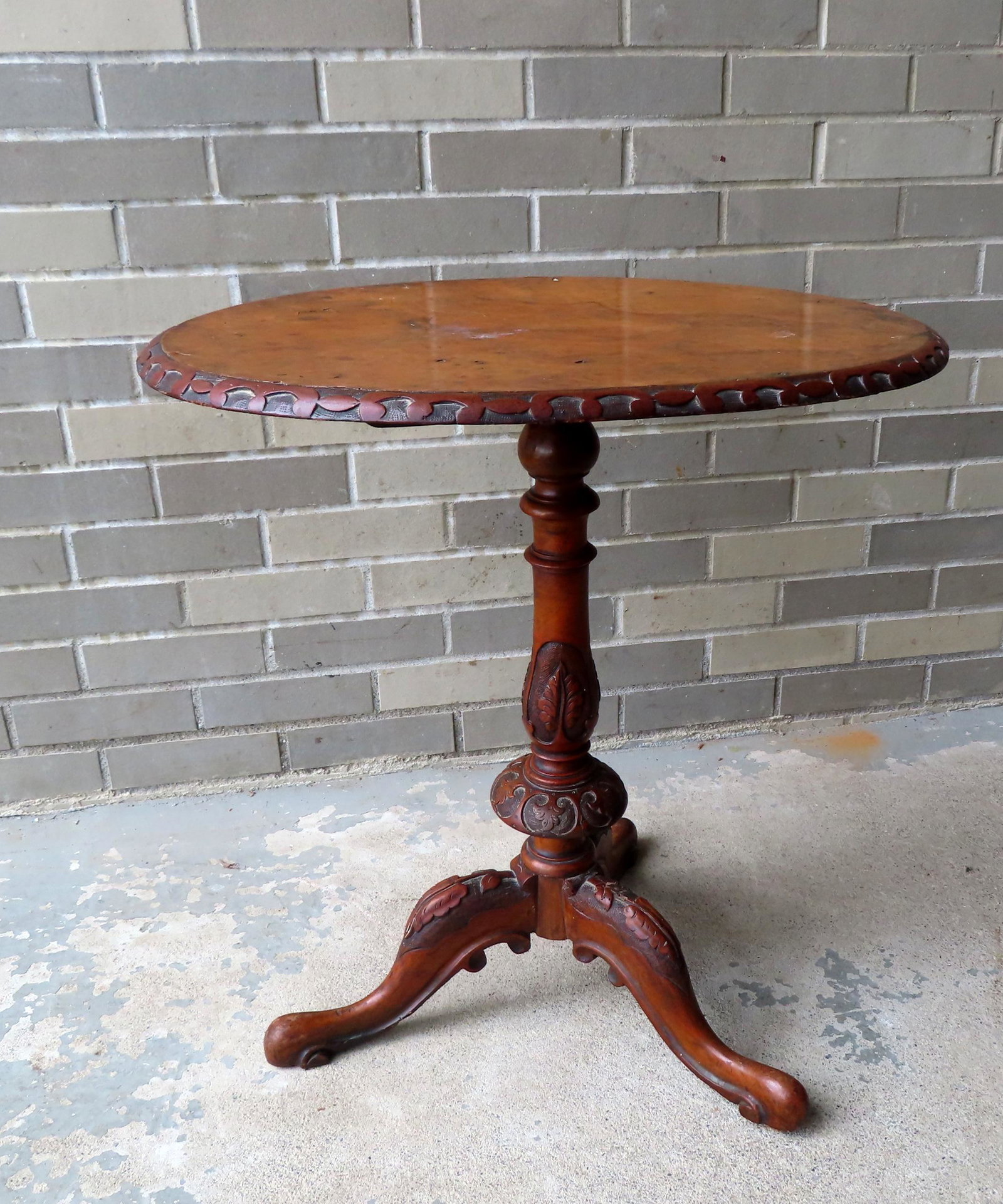 A fancy tilt top candlestand having a burl wood oval top, with a hand carved pedestal with acanthus: A fancy tilt top candlestand having a burl wood oval top, with a hand carved pedestal with acanthus decorations leading to legs with similar hand carved decorations ending in scrolled snake feet, prob