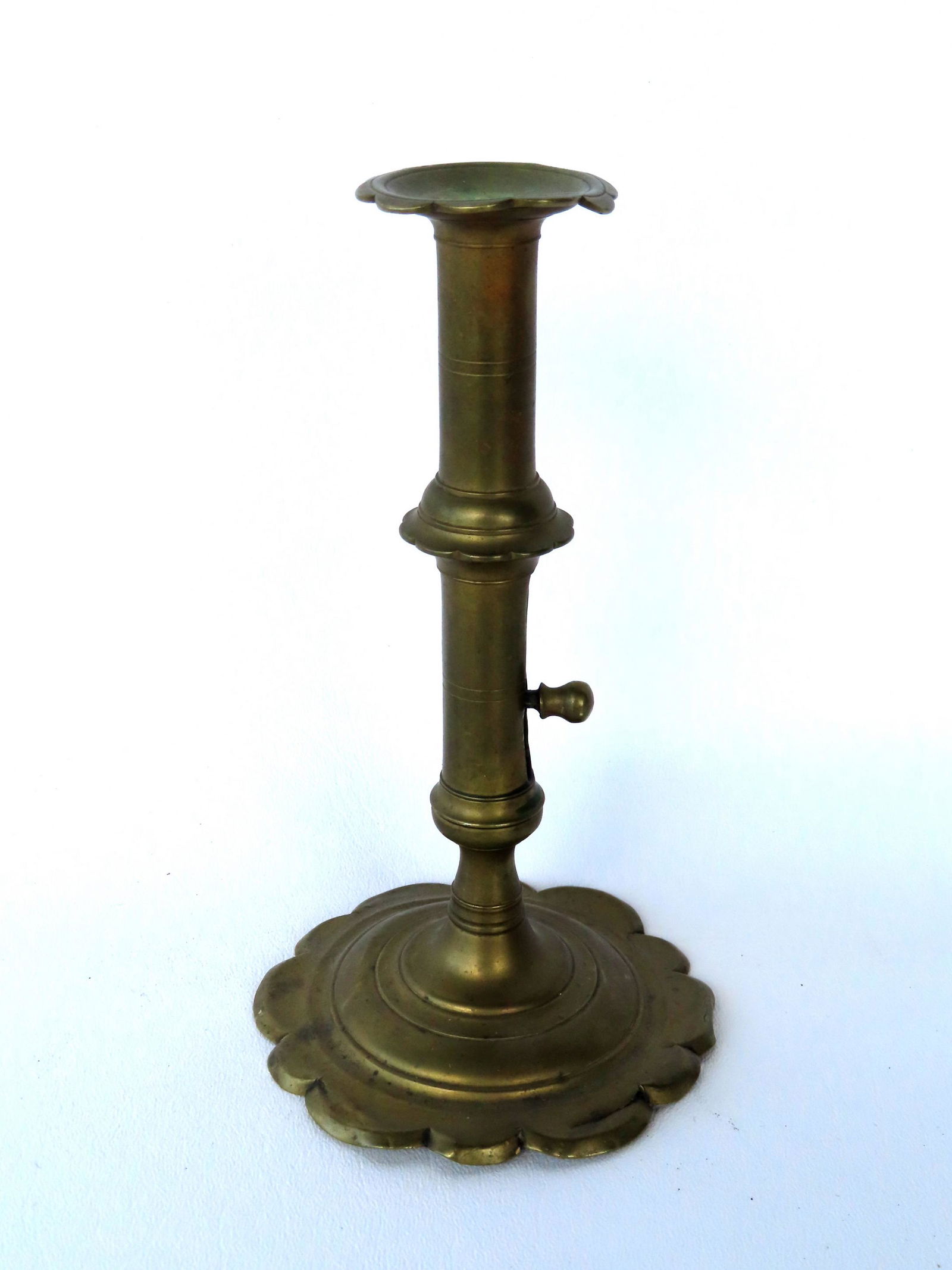 A continental brass pushup candlestick having a scalloped base and rim, probably English circa 1775 (1 of 4)