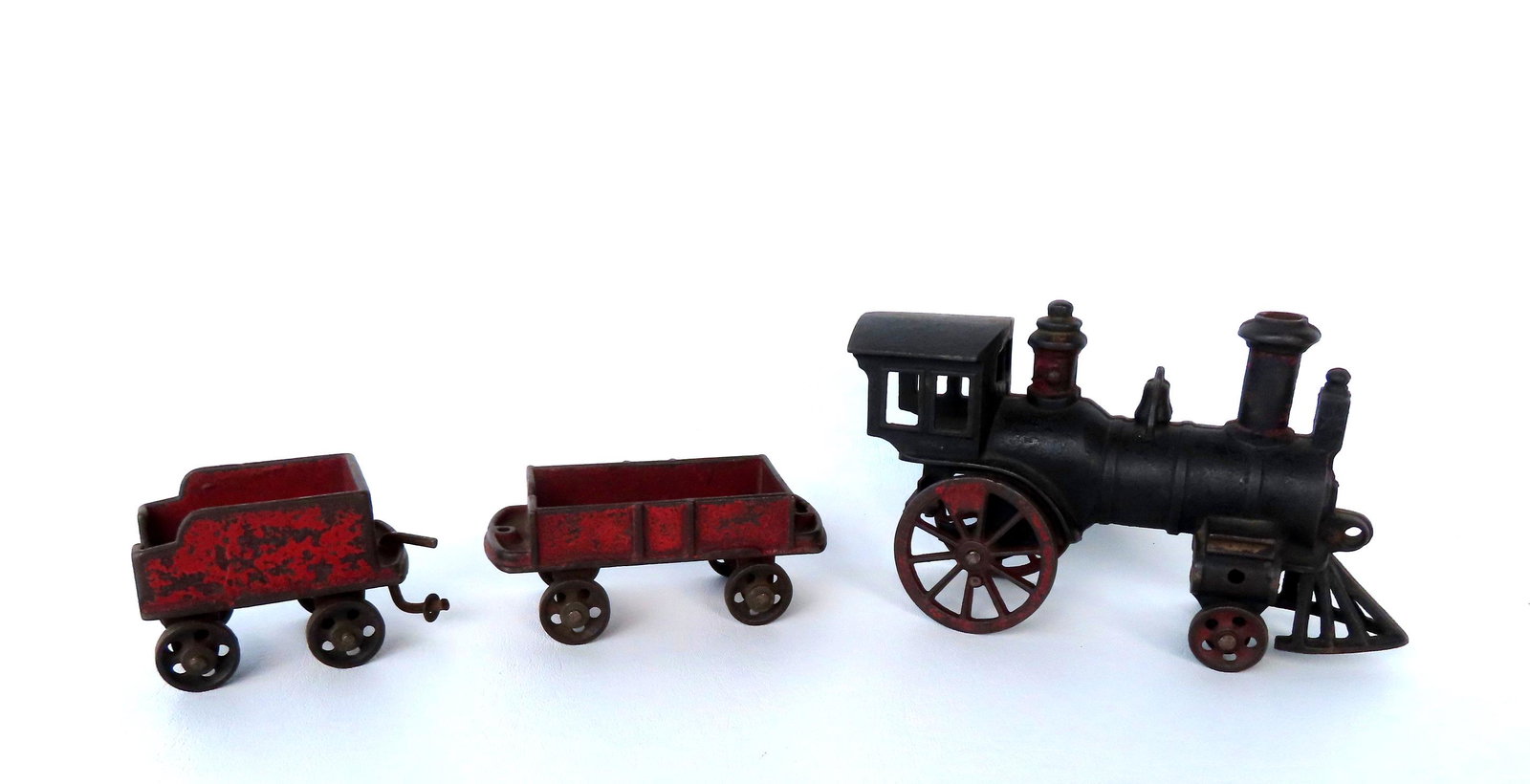 A cast iron toy steam locomotive with utility car and coal car, traces of original red paint. The: A cast iron toy steam locomotive with utility car and coal car, traces of original red paint. The engine appears to be marked "Pat'd June '80" and both cars marked "Pat'd May 25 / 1880 / Reiss'd / Mar