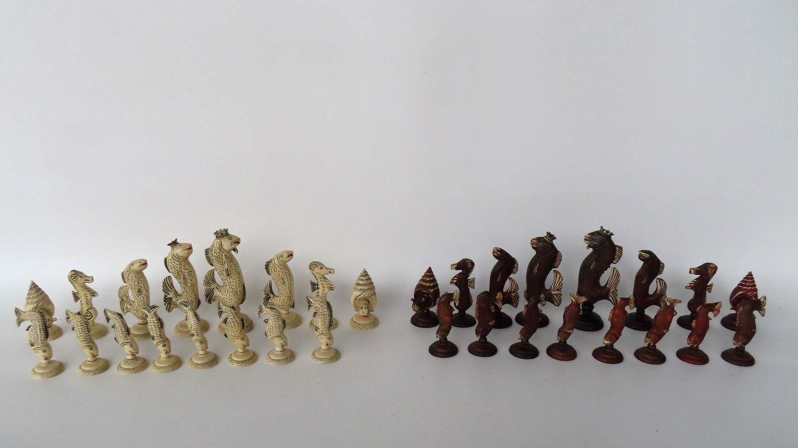 An unique chess set, the pieces appear to be bone, and are carved in marine life patterns including: An unique chess set, the pieces appear to be bone, and are carved in marine life patterns including a variety of fish and seashell designs, probably mid 20th century. The largest measures 4 7/8"H. Com