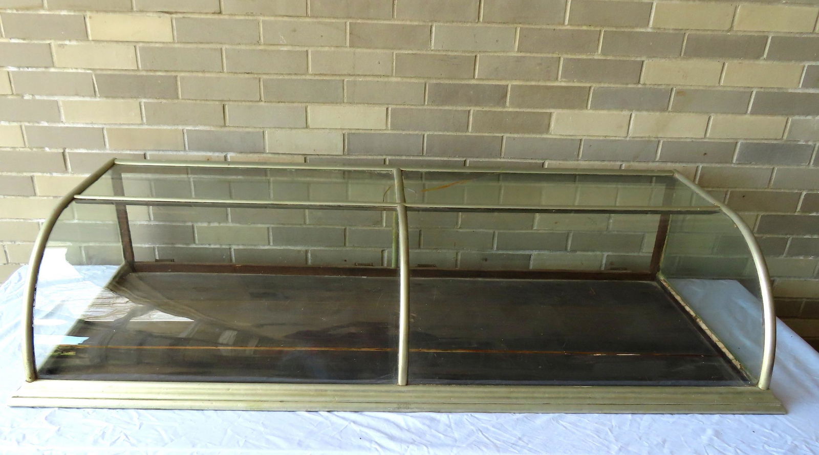 A table top glass showcase with curved front and nickel plated metal frame and signed "A. Blusch / (1 of 8)