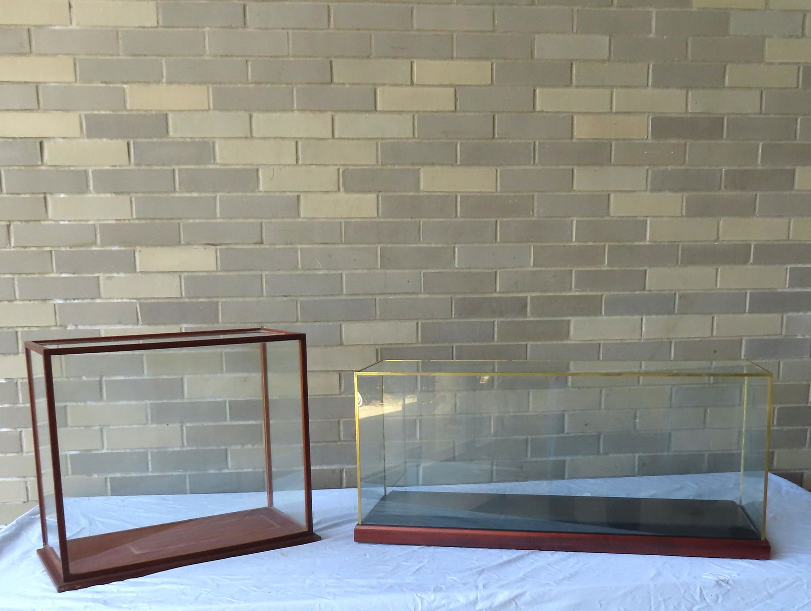 Two glass showcases for displaying ship models, both in very good condition. The smaller showcase: Two glass showcases for displaying ship models, both in very good condition. The smaller showcase with wooden frame measures 21"W x 9 1/2"D x 18 3/4"H - the larger with metal frame measures 34 38"W x