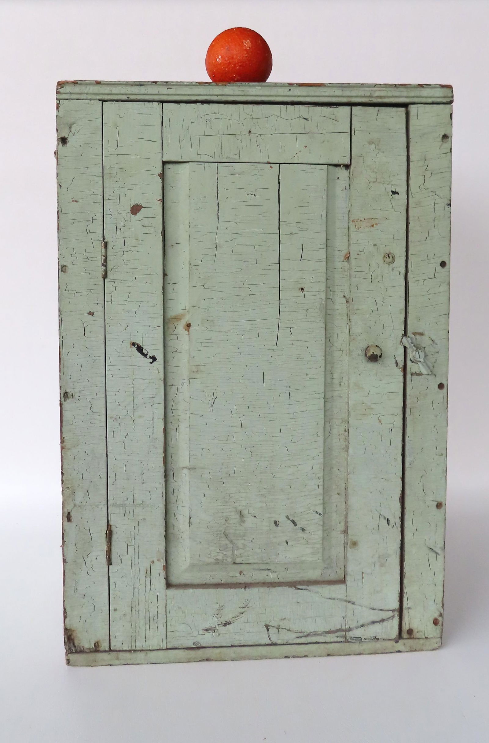A table top or wall cupboard with a singled paneled door in old light green paint and canted sides, (1 of 7)