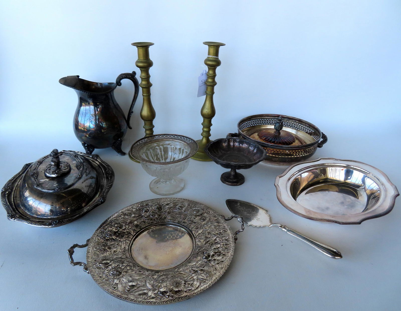 A grouping of silver plate and a pair of 19th century brass candlesticks. Includes, serving pieces, (1 of 9)