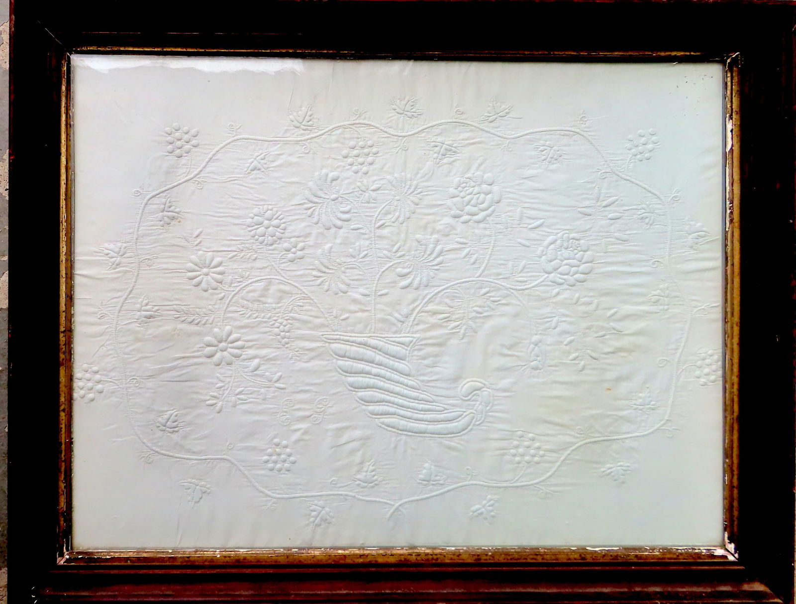 A framed white hand sewn trapunto crib quilt or wedding quilt fragment, decorated with cornucopia (1 of 6)