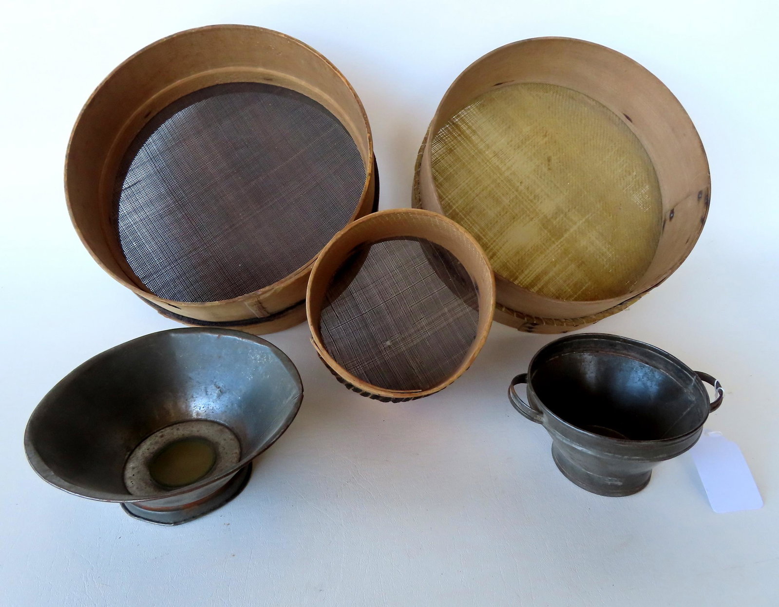 Grouping of 5 early sieves, 2 in tin with copper screens and 3 with circular wooden frames - 1 in: Grouping of 5 early sieves, 2 in tin with copper screens and 3 with circular wooden frames - 1 in woven grass and 2 in woven horse hair - the largest measures 12" diameter x 5 5/8"H. All 19th century 