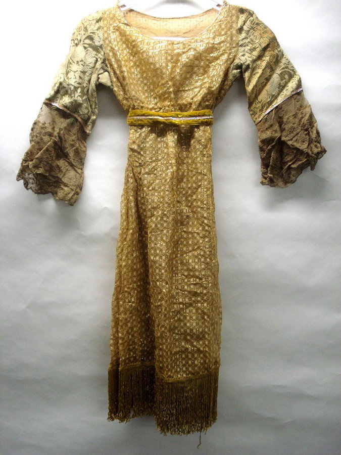 Two child's theatrical dresses.: Two child-size theatrical dresses: One with small sequins around collar, lace arms, lace dress body trimmed with small gold lace squares, dress ending in tassels circa 1950, the other hand sewn with s