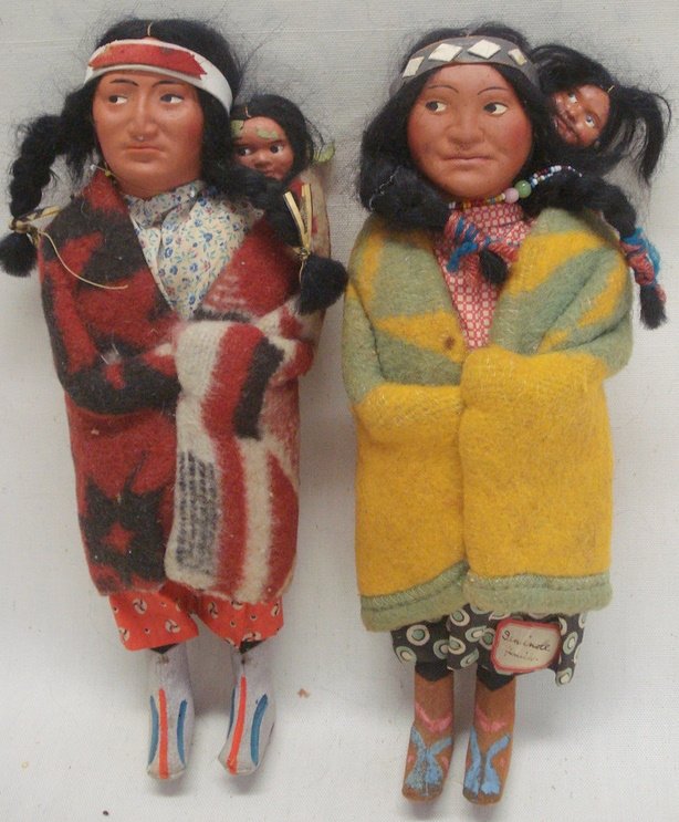 Two Skookum Indian dolls - original costumes - eac: Two Skookum Indian dolls - original costumes - each with a papoose - one with original paper "Skookum Indian" label on foot. Each 10.5"H. Very good condition. Note - old sticker attached to doll "Semi