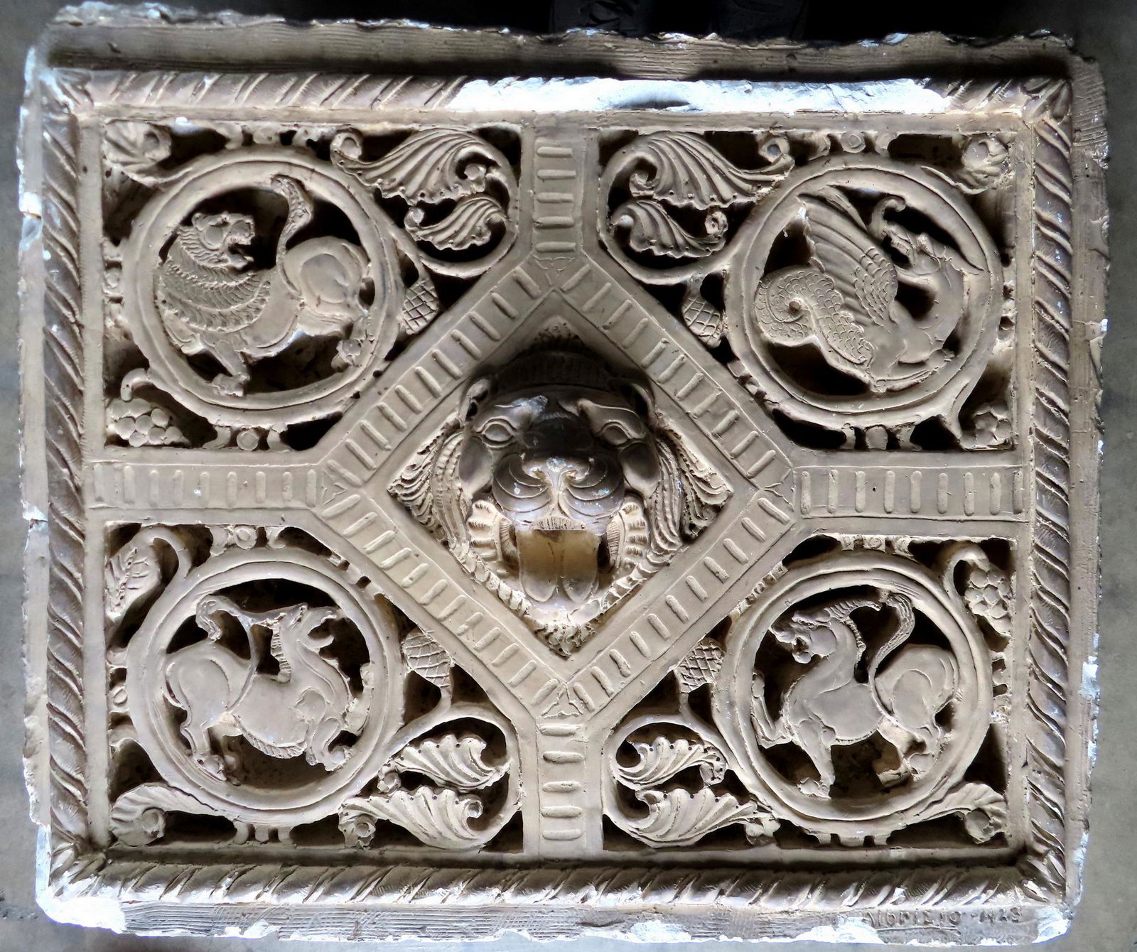 A large architectural plaster sculpture with a central image of a lion's head surrounded by griffins (1 of 11)