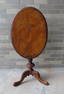 A fancy continental tilt top candlestand having a burl wood oval top, with a hand carved pedestal