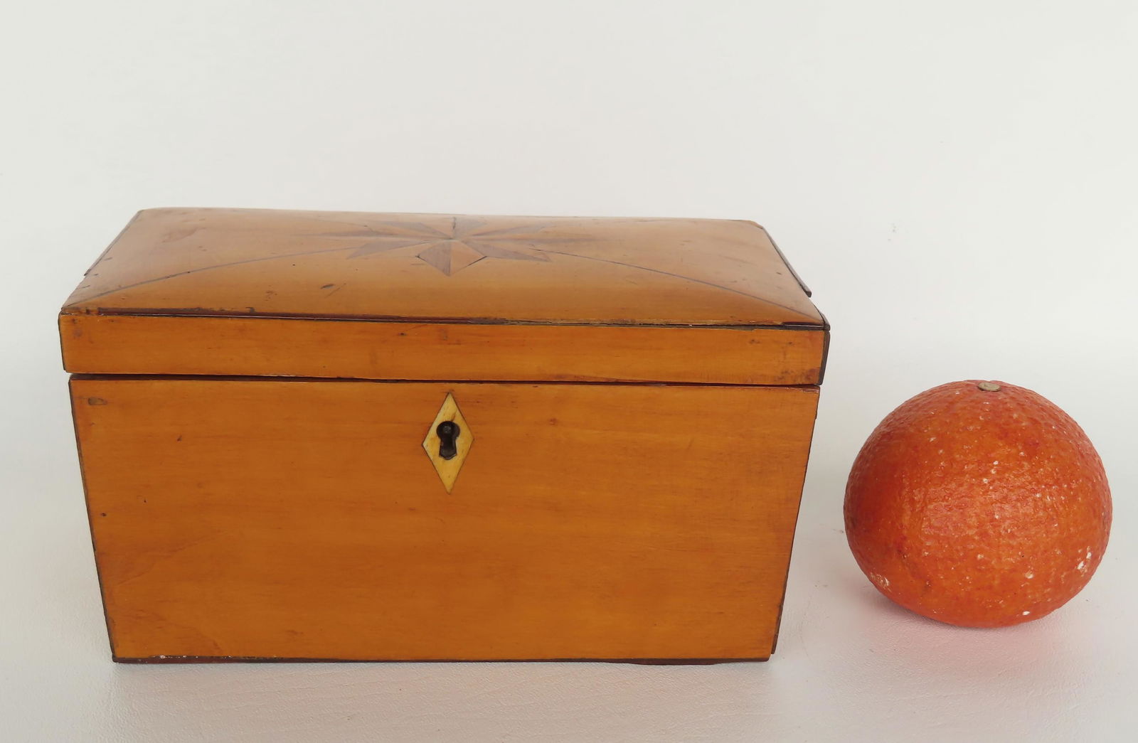 A rectangular shaped tea caddy with inlaid star on center of lid with rays extending to corners,: A rectangular shaped tea caddy with inlaid star on center of lid with rays extending to corners, bone escutcheon (no key), grain painted tortoise shell design on underside of lid which is slightly dom
