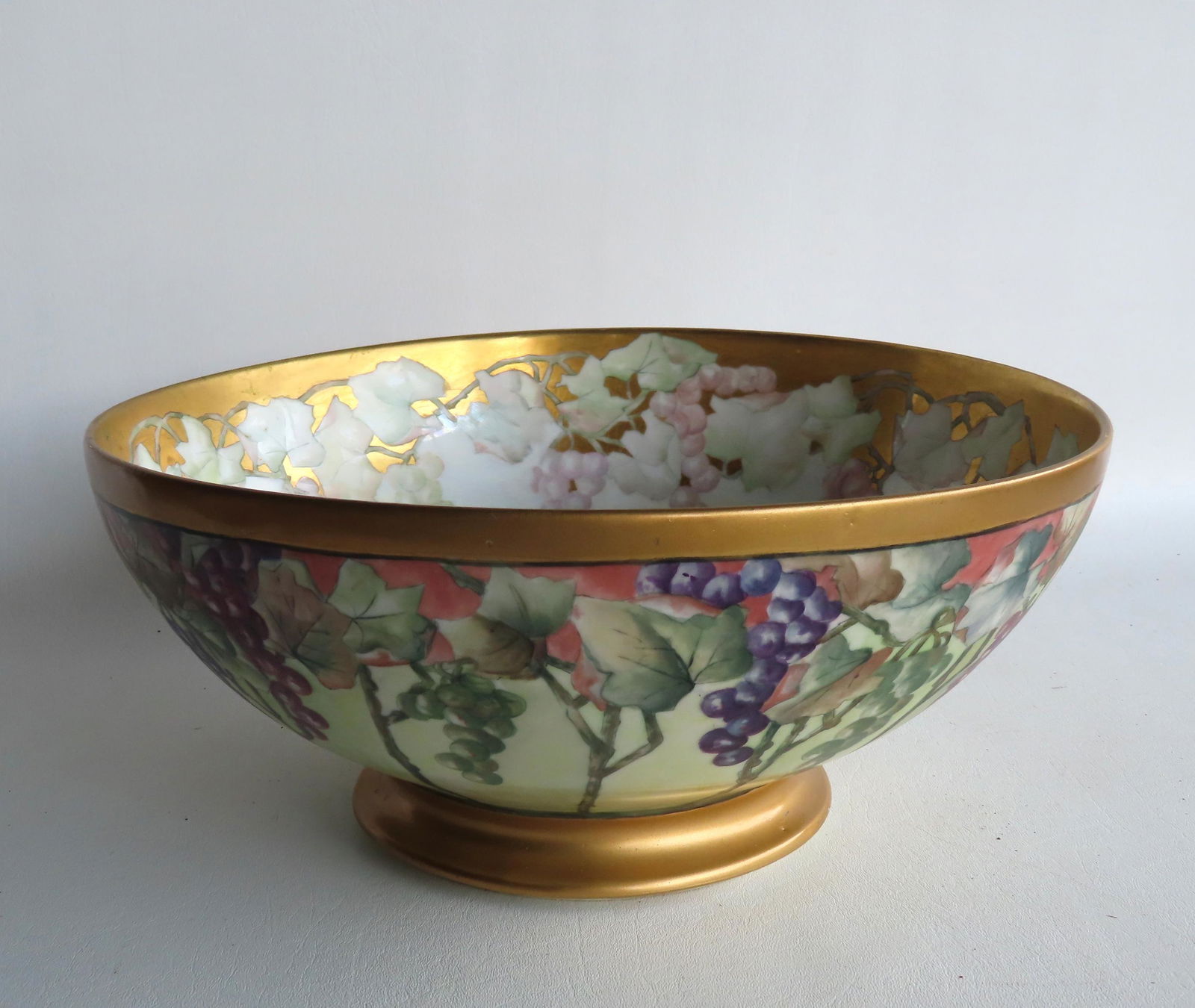 A Limoges porcelain punch bowl with hand painted grapes and vines around the body and having a (1 of 7)