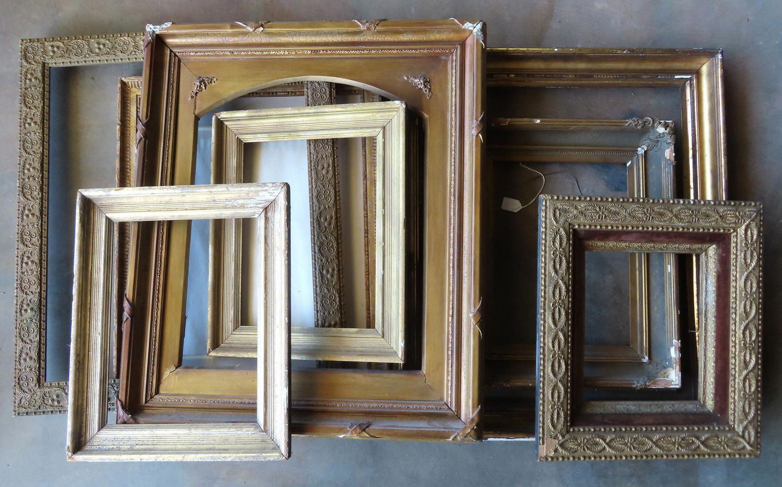 Grouping of 8 mostly early gilt gesso picture frames some needing restoration work: Grouping of 8 mostly early gilt gesso picture frames some needing restoration work, early to late 19th century. The largest, in lemon gold, measures 28 1/4" x 33". One frame with "Kraushaar Galleries