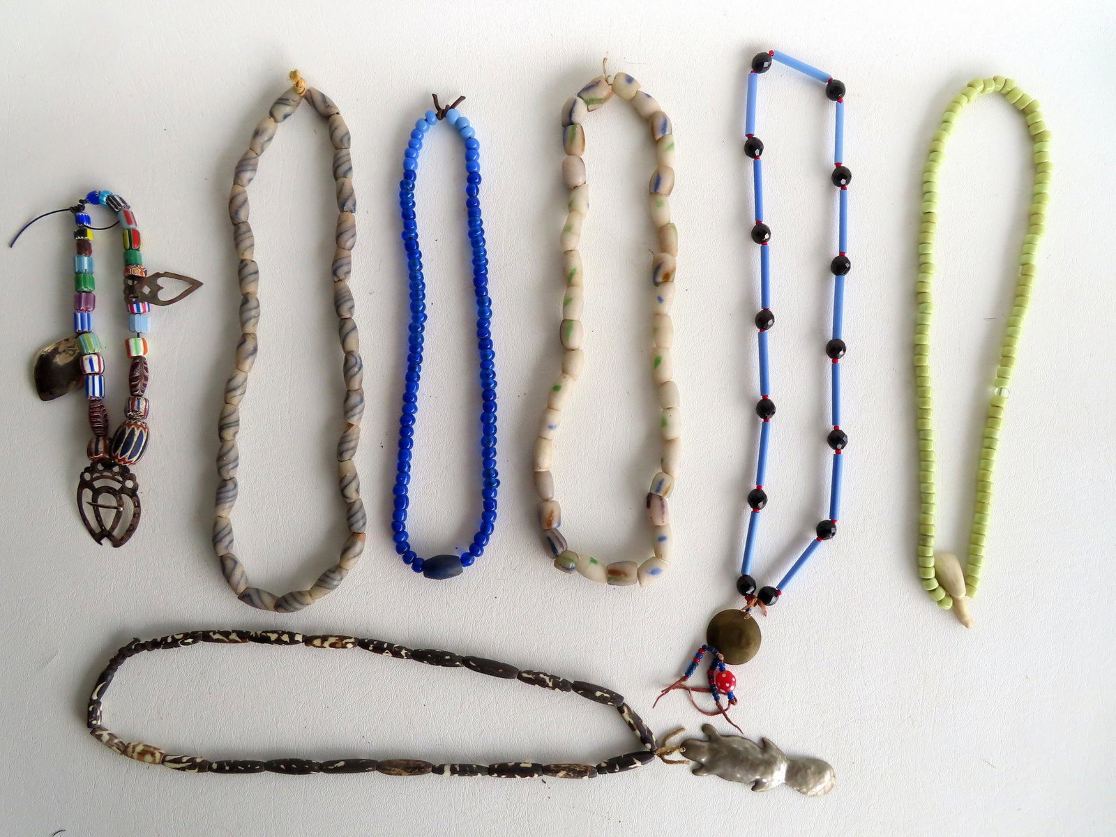 Grouping of 7 indigenous peoples hand made beadwork necklaces, some possibly Native American,: Grouping of 7 indigenous peoples hand made beadwork necklaces, some possibly Native American, constructed of stone, colored glass, and bone. One appears to be animal horn with a beaver metal pendant.