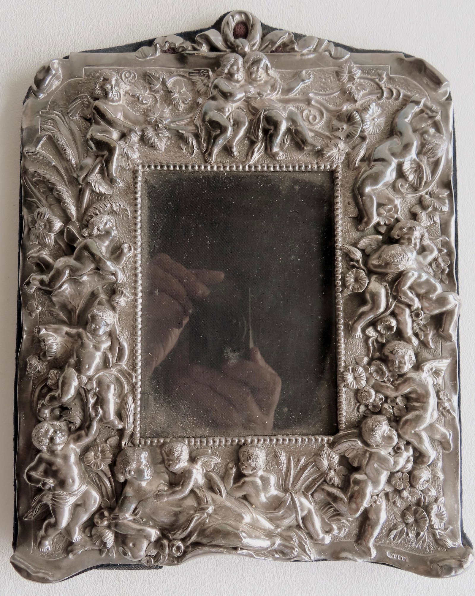 Ornate Neil Lasher silver picture frame, late 20th century.: An ornate Neil Lasher silver picture frame, late 20th century. Hallmarked NLS for Neil Lasher Silver. The frame profusely decorated with cherubs, and flowers on vines. Very good condition. Overall siz