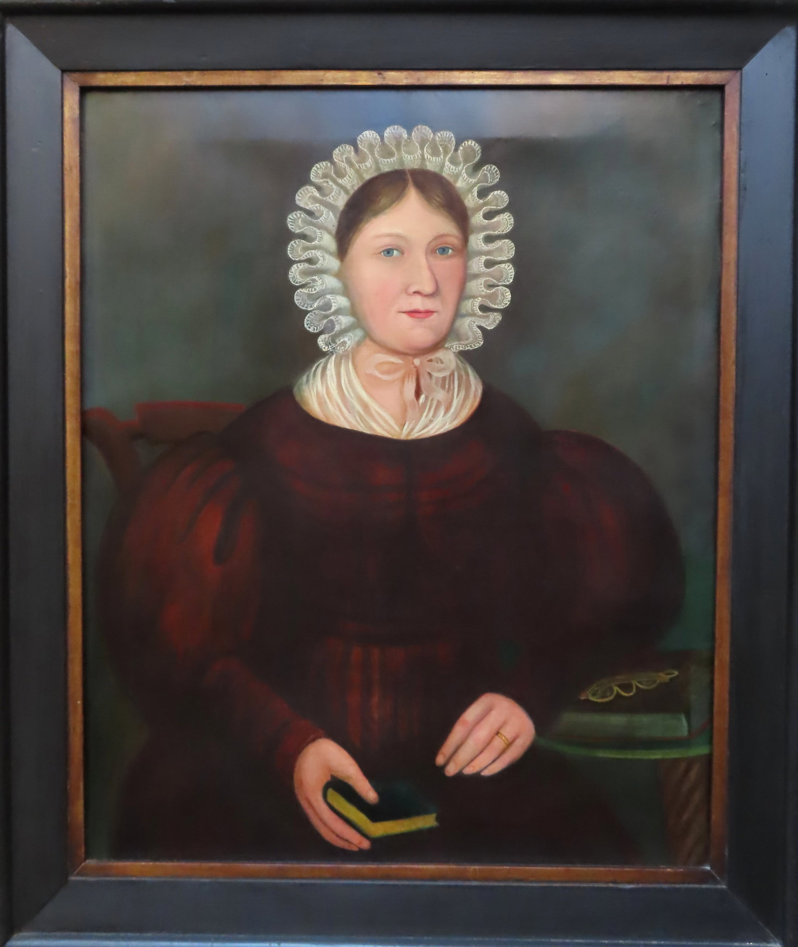 A wonderful O/C portrait of a young woman wearing a curled lace bonnet and blue dress, and holding: A wonderful O/C portrait of a young woman wearing a curled lace bonnet and blue dress, and holding a book in her right hand, probably early 19th century. Relined, some restoration along the bottom (se
