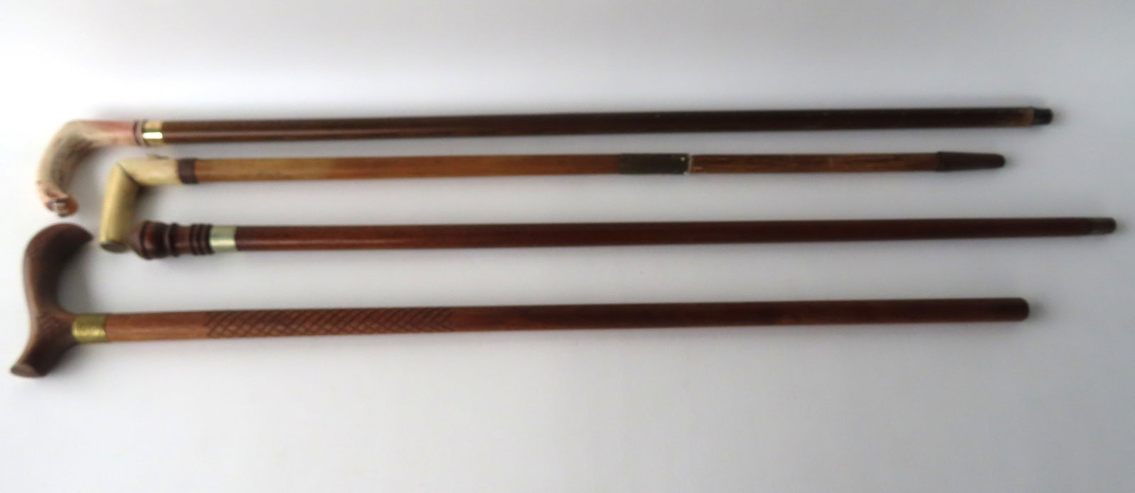 Grouping of 4 walking sticks including one with a carved bone handle with embossed dog head on the: Grouping of 4 walking sticks including one with a carved bone handle with embossed dog head on the side (has an old repair to the wooden staff - late 19th century) - the other 3 canes are likely early