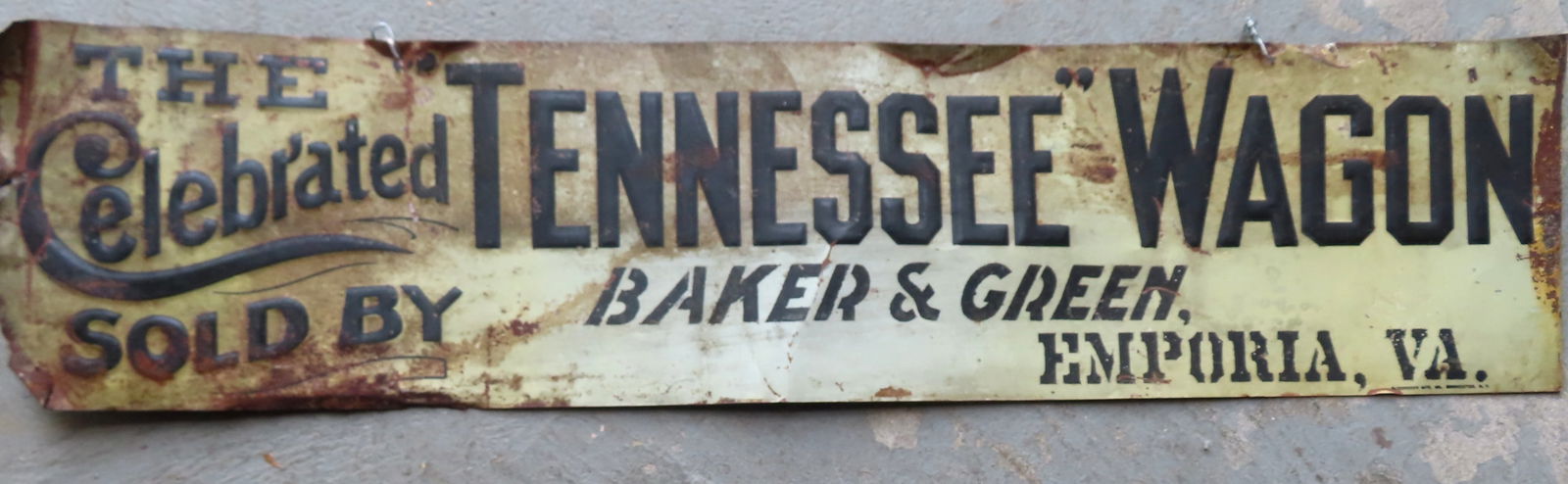 A vintage tin advertising sign marked "THE Celebrated TENNESSEE WAGON / SOLD BY BAKER & GREEN / (1 of 6)