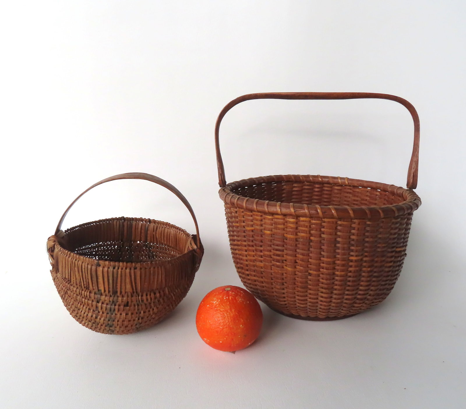 A Nantucket basket with typical swivel handle and circular wooden base, very good patination. Some: A Nantucket basket with typical swivel handle and circular wooden base, very good patination. Some loss of caning along the top rim, 1 piece of caning with break on side hardly noticeable, overall ver