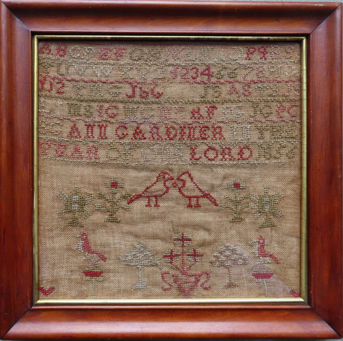An alphabet and pictorial sampler signed "ANN Gardiner In The Year Of Our Lord 1856" - minor moth: An alphabet and pictorial sampler signed "ANN Gardiner In The Year Of Our Lord 1856" - minor moth damage and overall good condition. Total frame 14 1/2" x 14 1/4".